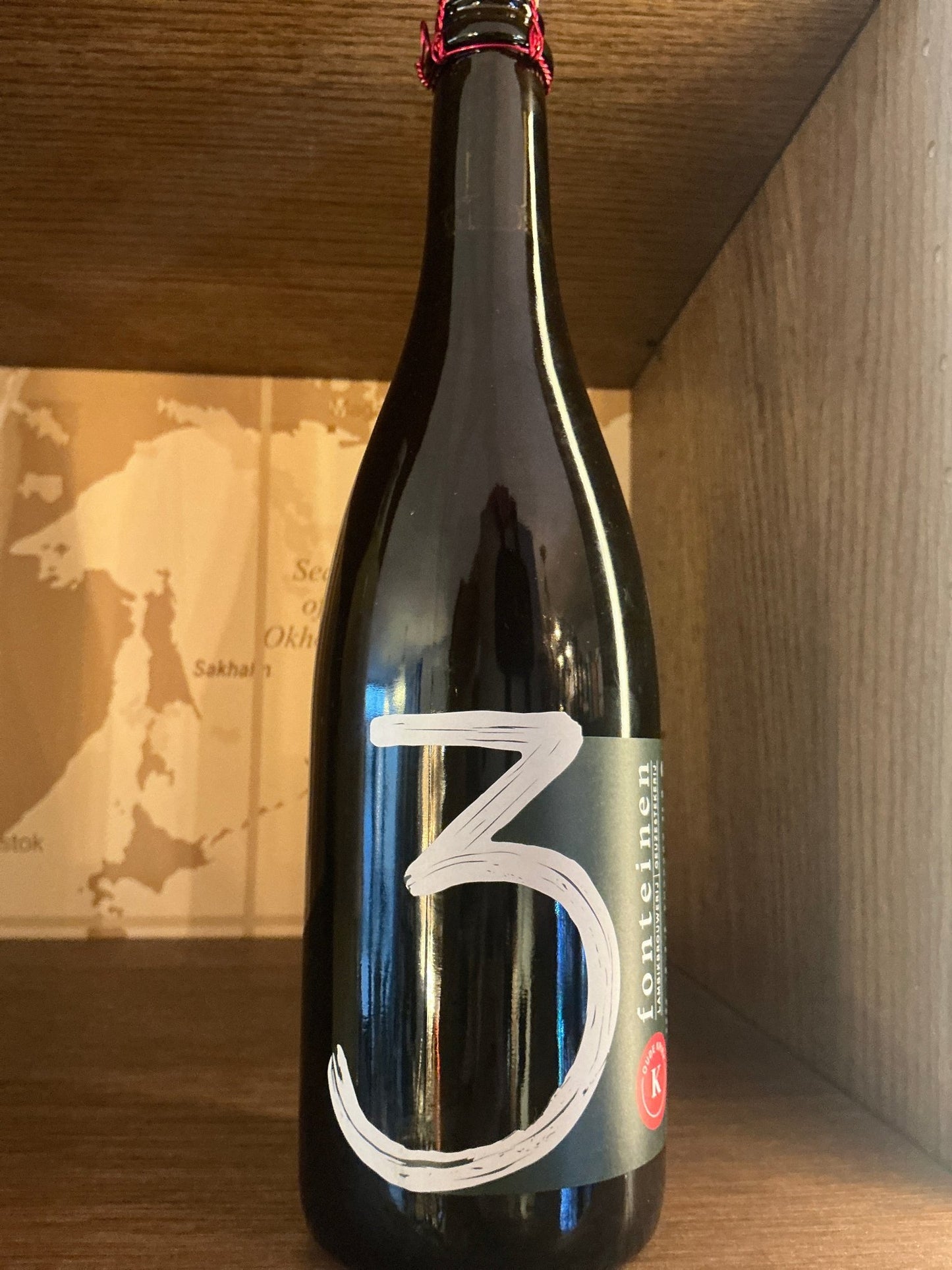Dark glass bottle of Drie Fonteinen Oude Kriek 22/23 craft beer with large white "3" on front label, sealed with red wax.