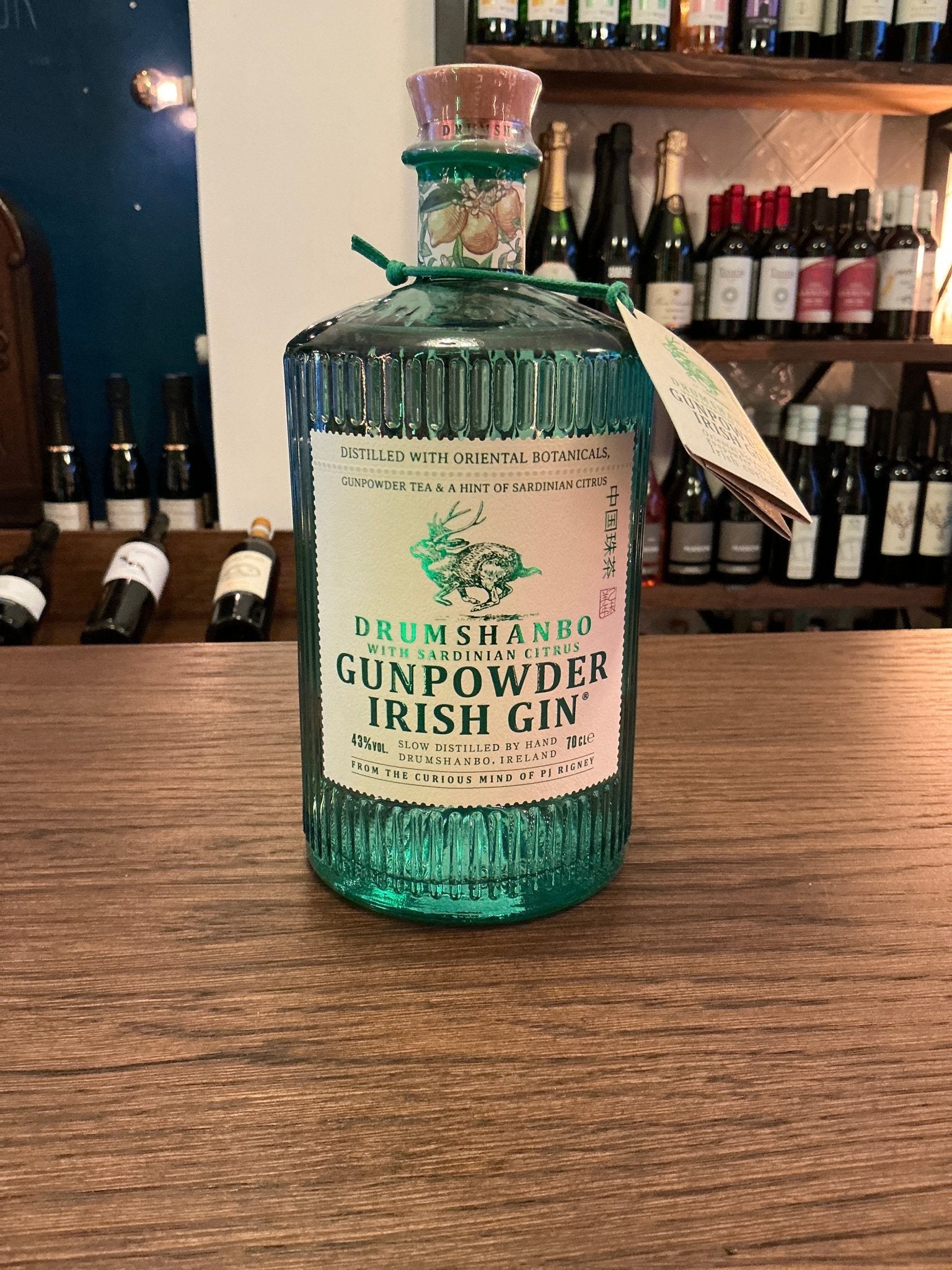 Drumshanbo Gunpowder Irish Gin in ribbed green glass bottle with cork stopper, labeled bold citrus and oriental botanicals,.
