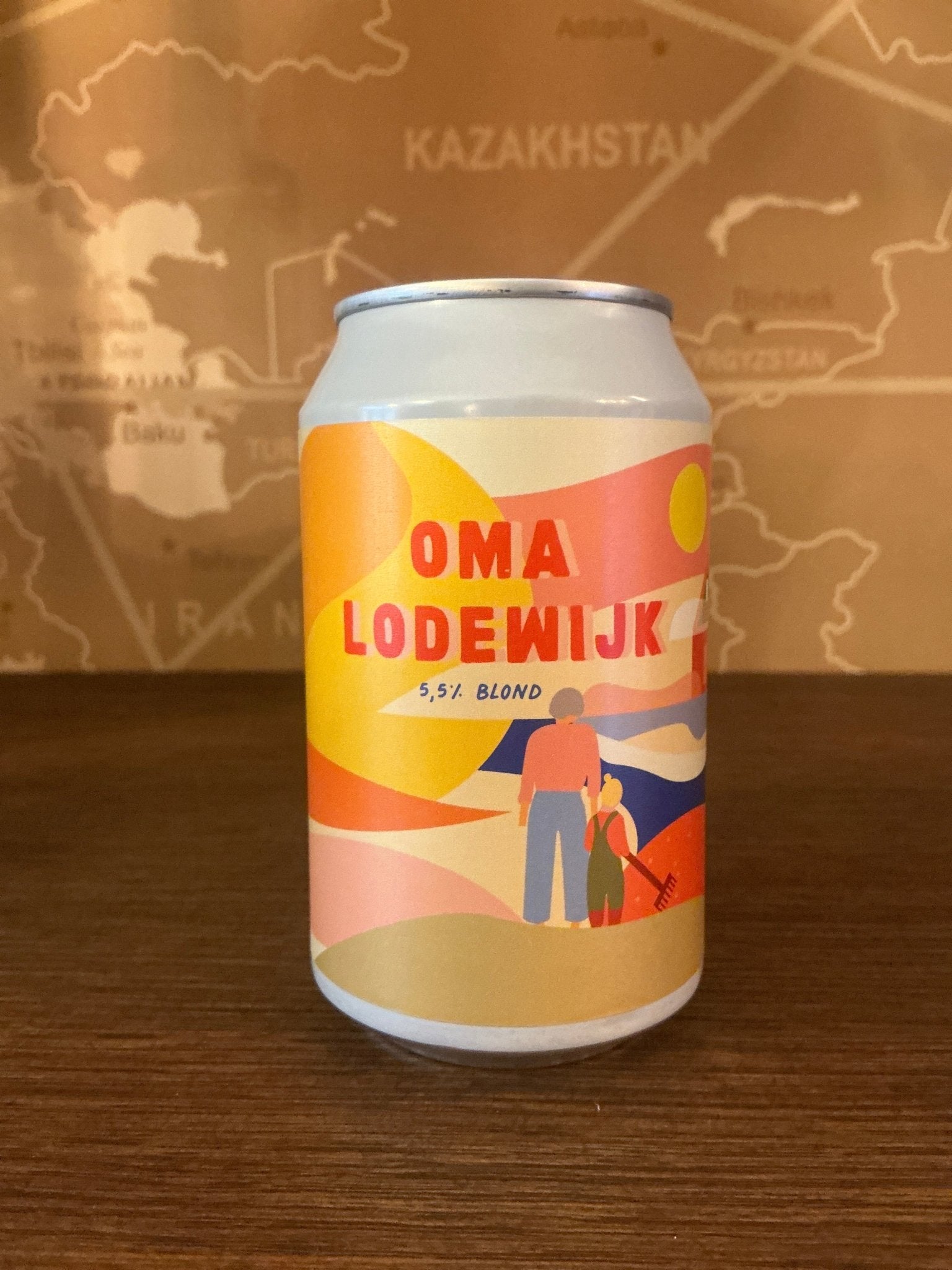 White aluminum can with a colorful, modern label featuring warm tones of yellow, orange, and pink, displaying the name "Oma.