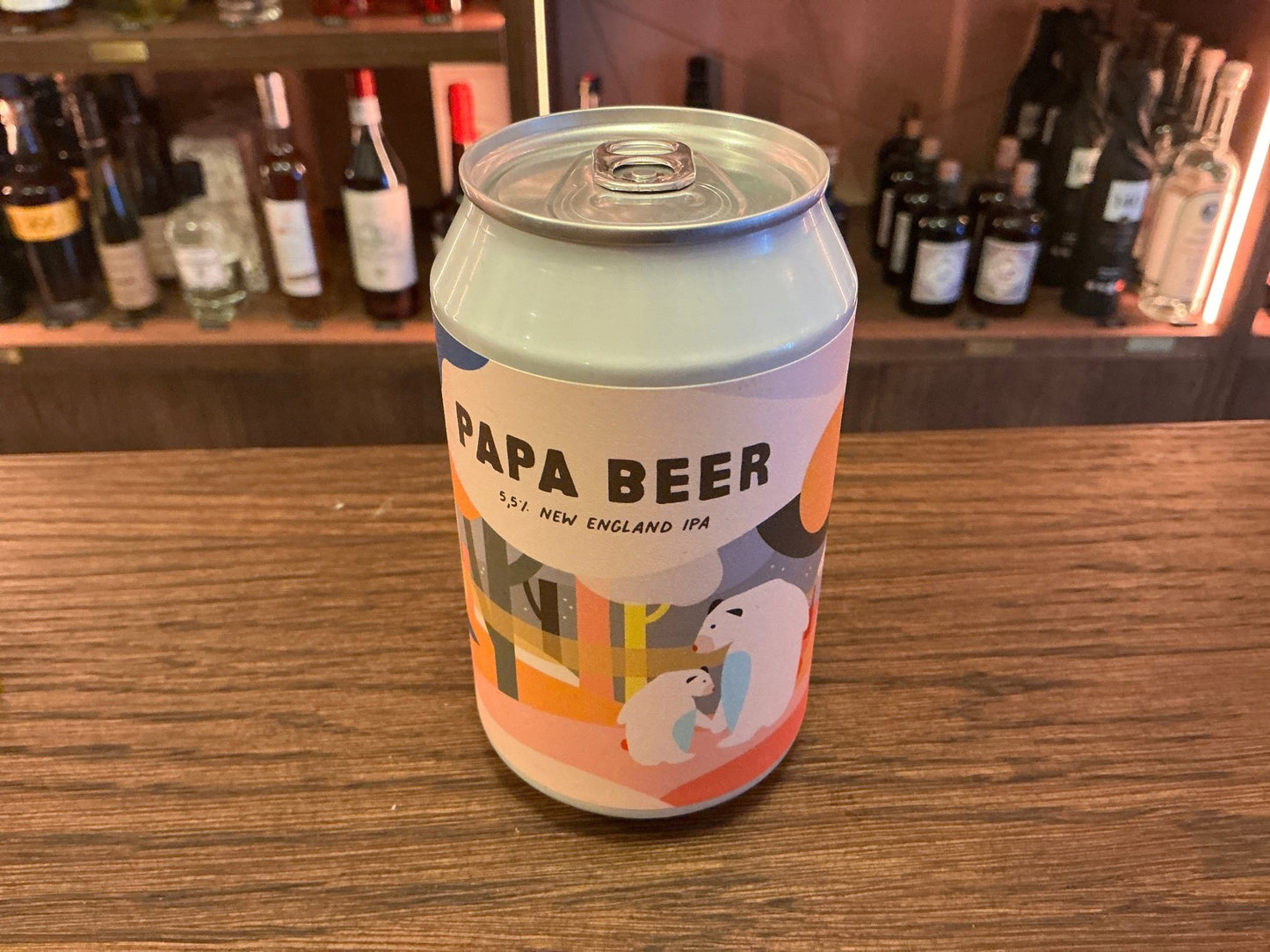 Eleven Papa Beer craft beer can with vibrant orange and beige label featuring abstract art on wooden bar counter.