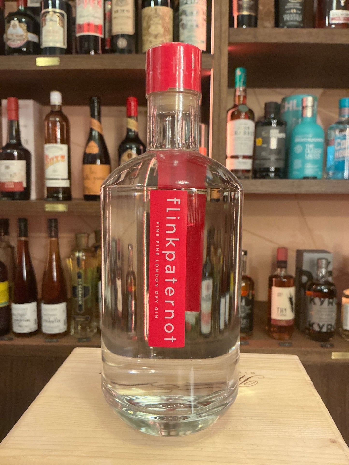 Clear glass bottle of Flinkpaternot Dutch Gin with bright red label and cap, showcasing premium small-batch distilled.