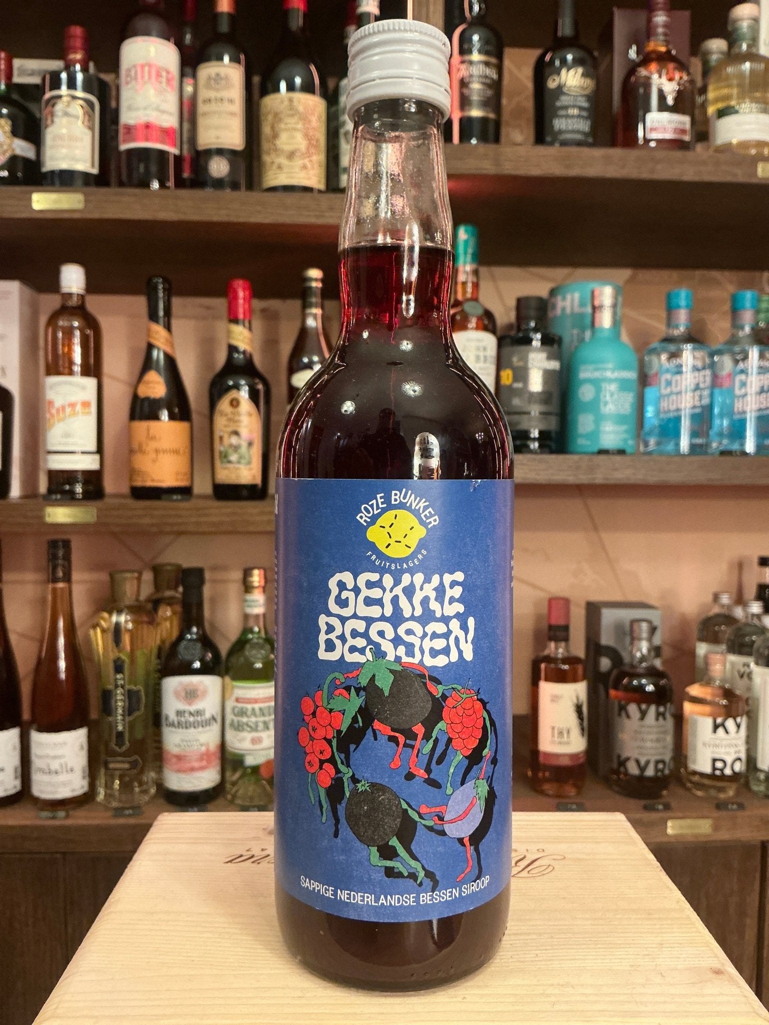 Gekke Bessen Big cordial bottle with dark red liquid, blue label featuring botanical illustration, artisan Dutch specialty.