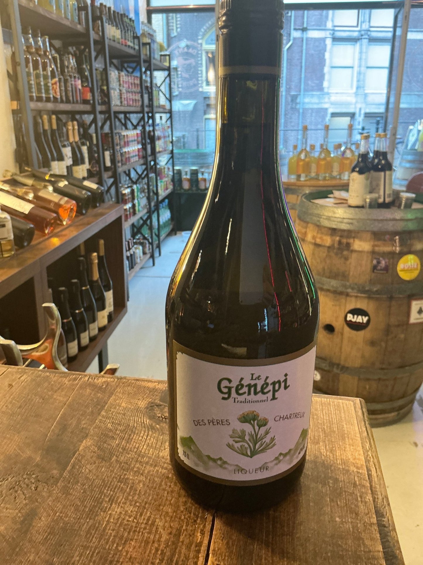 Genepi des Peres Chartreux herbal liqueur bottle with botanical label on rustic wooden table in specialty spirits store.
