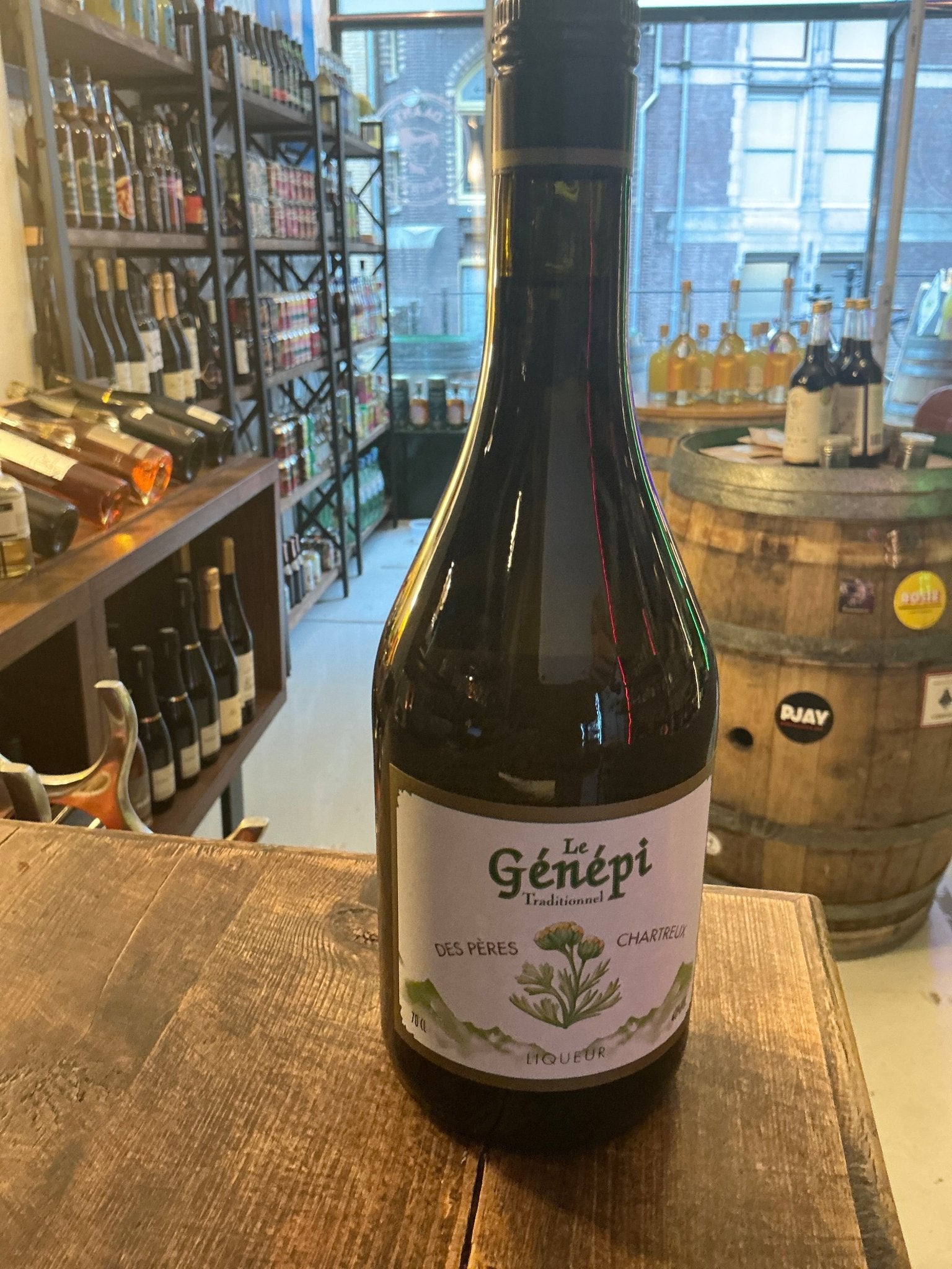 Genepi des Peres Chartreux herbal liqueur bottle with botanical label on rustic wooden table in specialty spirits store.
