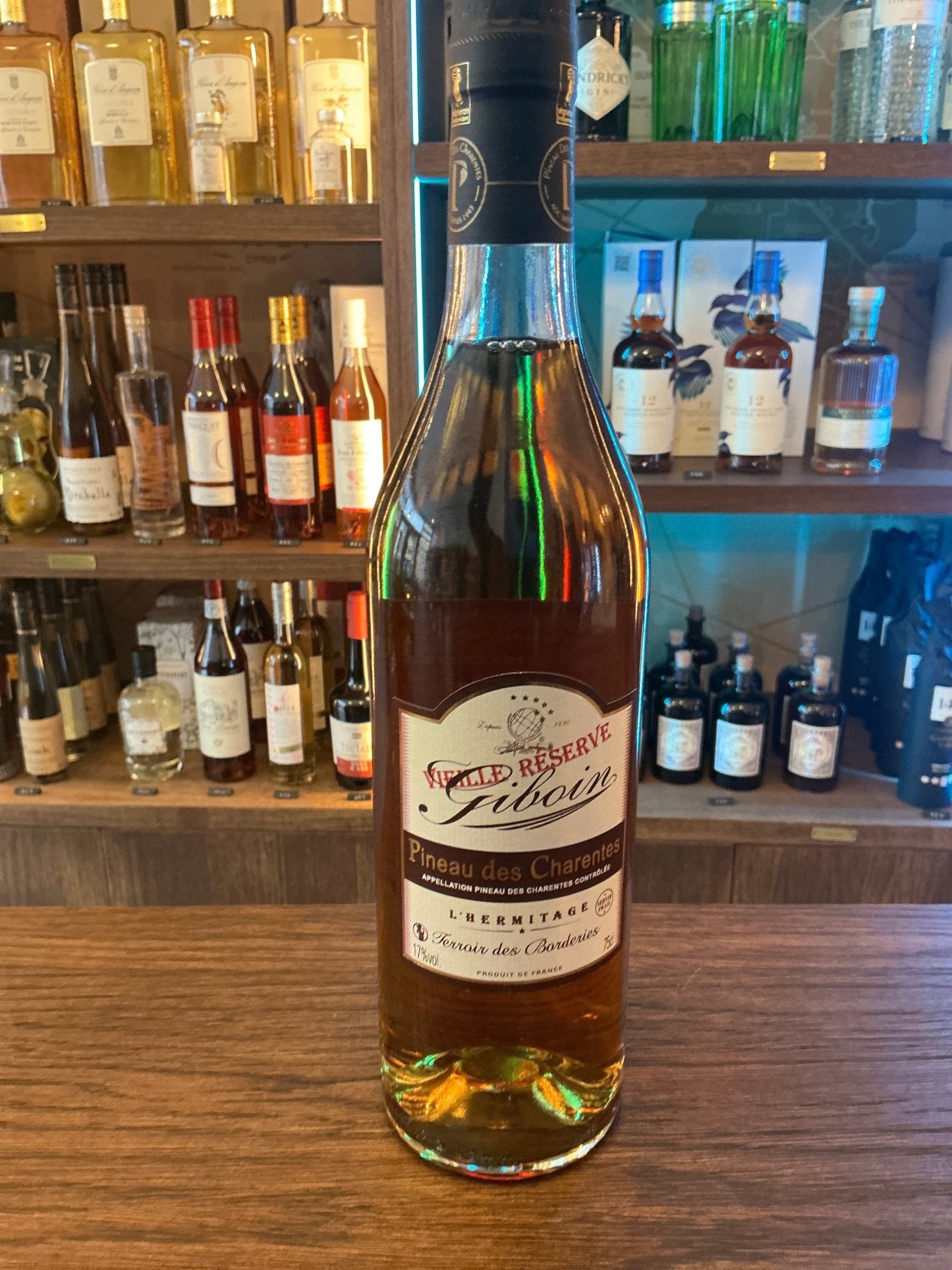 Giboin Pineau Blanc Vieille Reserve premium aged brandy bottle with golden amber liquid on wooden surface, artisanal.