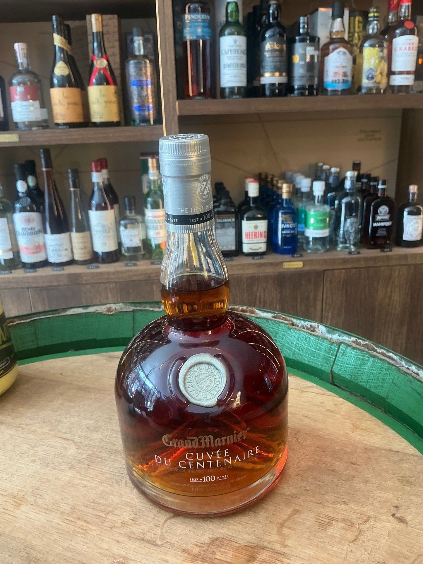 Grand Marnier Cuvée du Centenaire premium aged liqueur bottle with rich amber color on wooden barrel, artisan specialty.