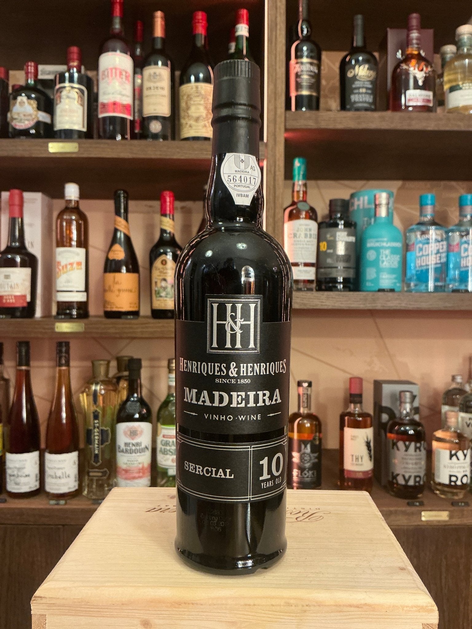 Henriques & Henriques Madeira 10 Year Old Sercial wine bottle with black label, premium aged fortified spirit on wooden.