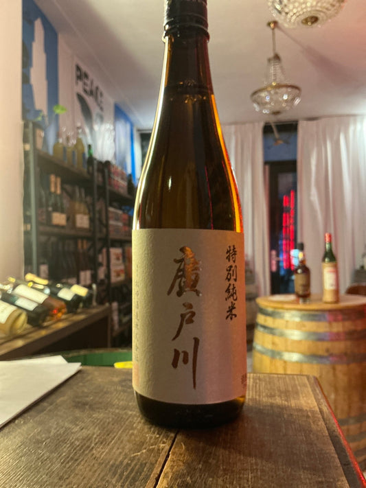 Hirotogawa Tokubetsu Junmai premium sake bottle with minimalist beige label and black Japanese calligraphy on wooden table.