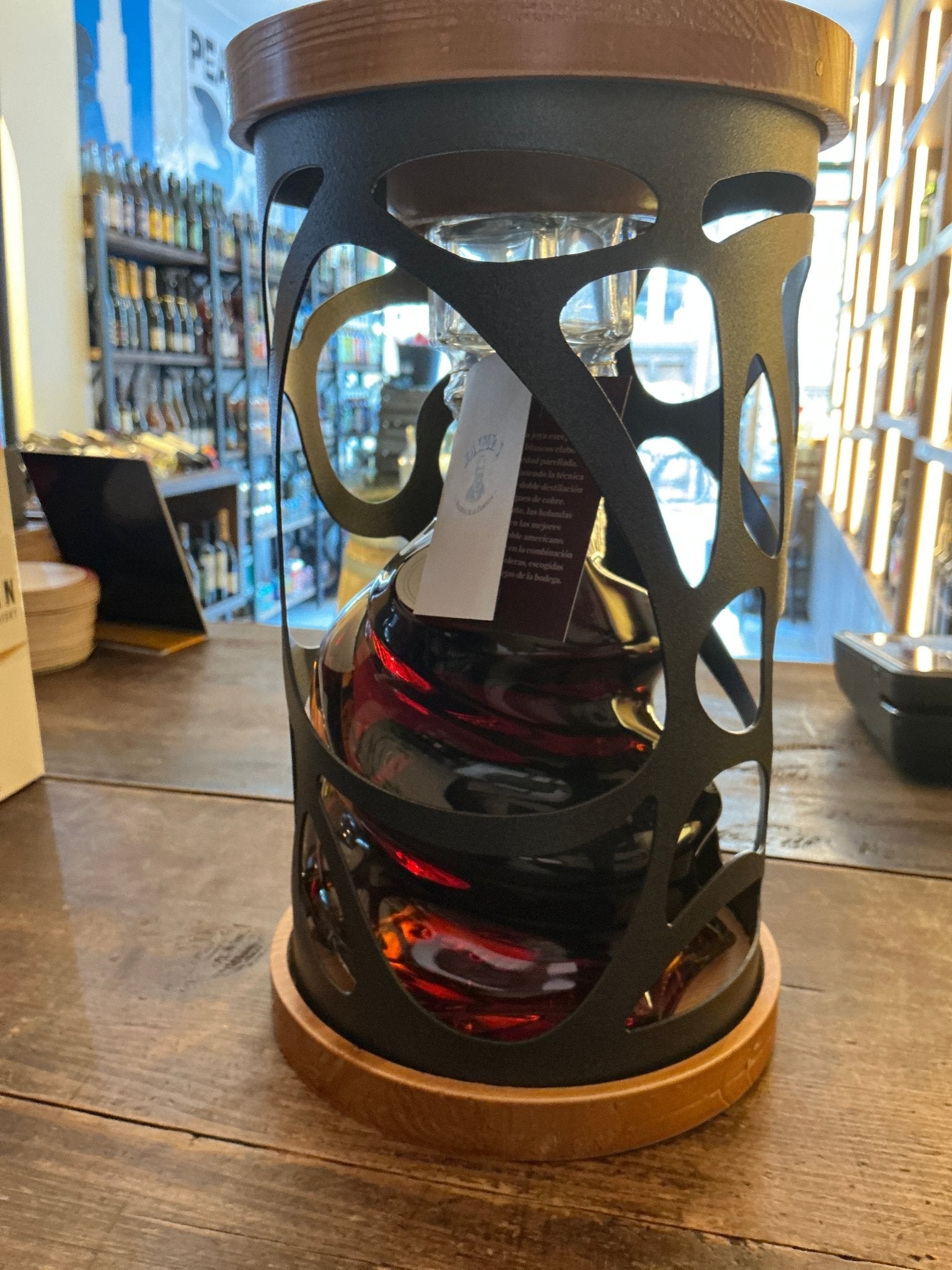 Premium Jaime I Brandy bottle encased in ornate black metal cage with wooden top and base, showcasing rich amber aged.