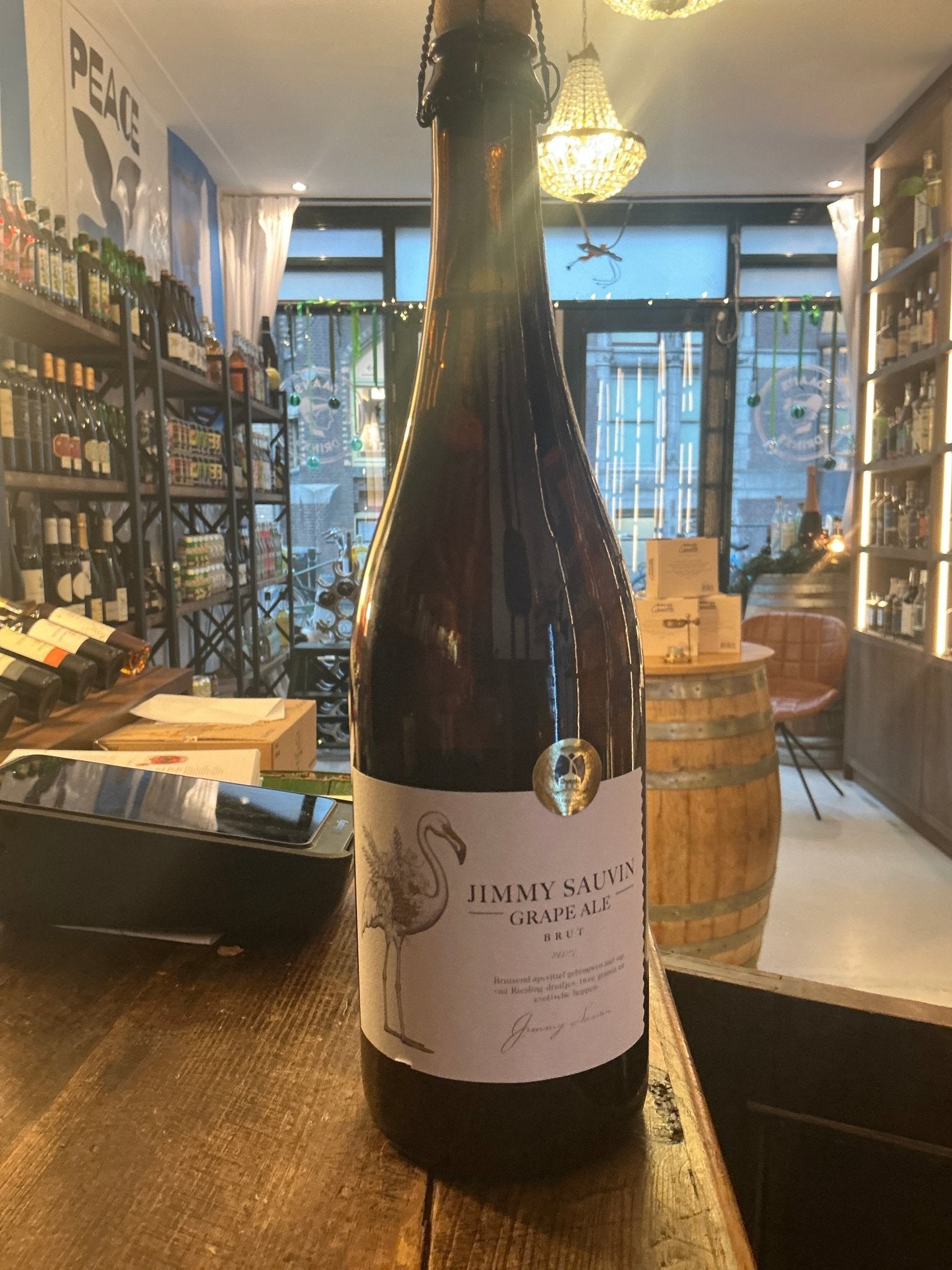 Tall brown glass bottle of Jimmy Sauvin Grape Ale Brut 2023 with white label, artisan craft beer inspired by botanical and.