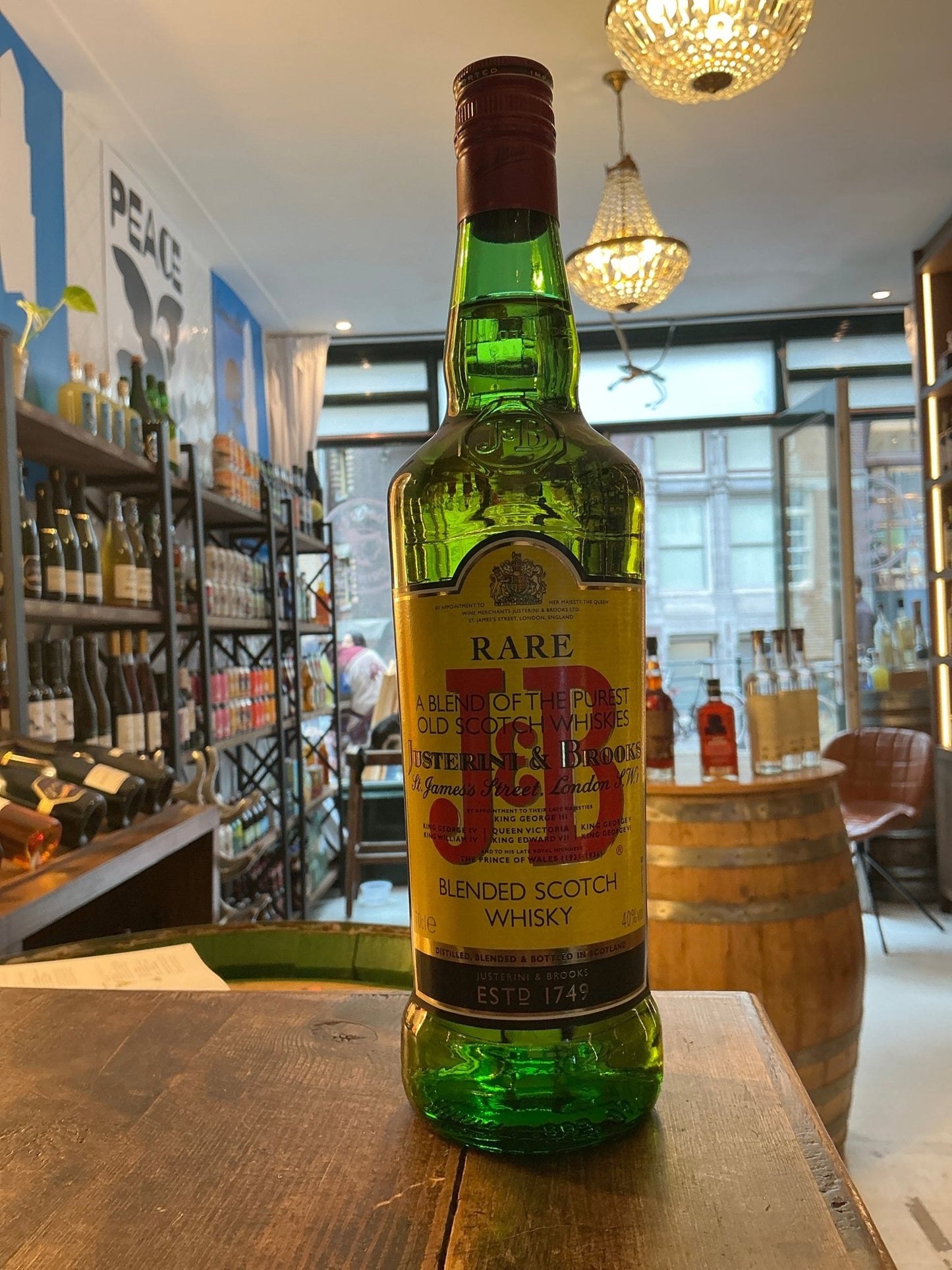 Green glass bottle of Justerini & Brooks J&B Blended Scotch Whisky with beige and red label, artisan small batch premium.