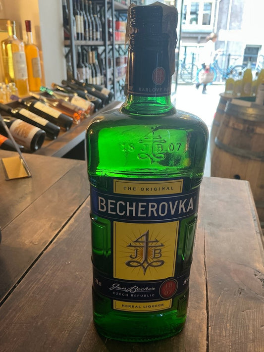Green glass bottle of Karlsbader Becherovka herbal liqueur with black cap, Dutch artisanal design, botanical spiced label on .