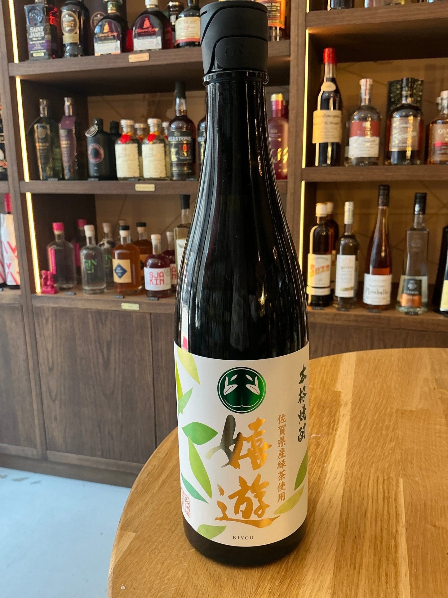 Premium artisanal Kiyou Honkaku Shochu by Munemasa Shuzo in sleek black bottle with white label and green leaf design,.