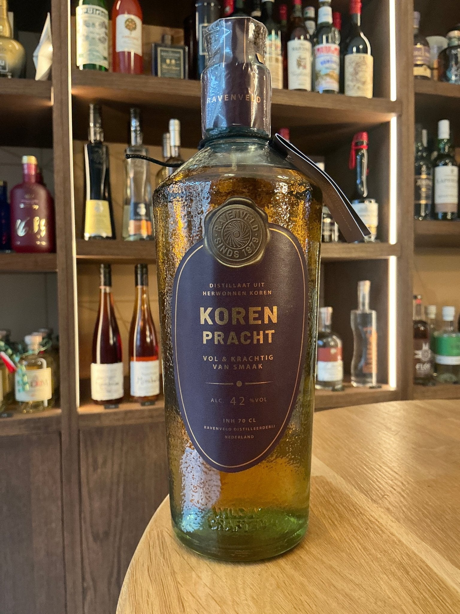 KorenPracht premium Dutch whisky distillate bottle with deep blue label and gold accents on wooden table.