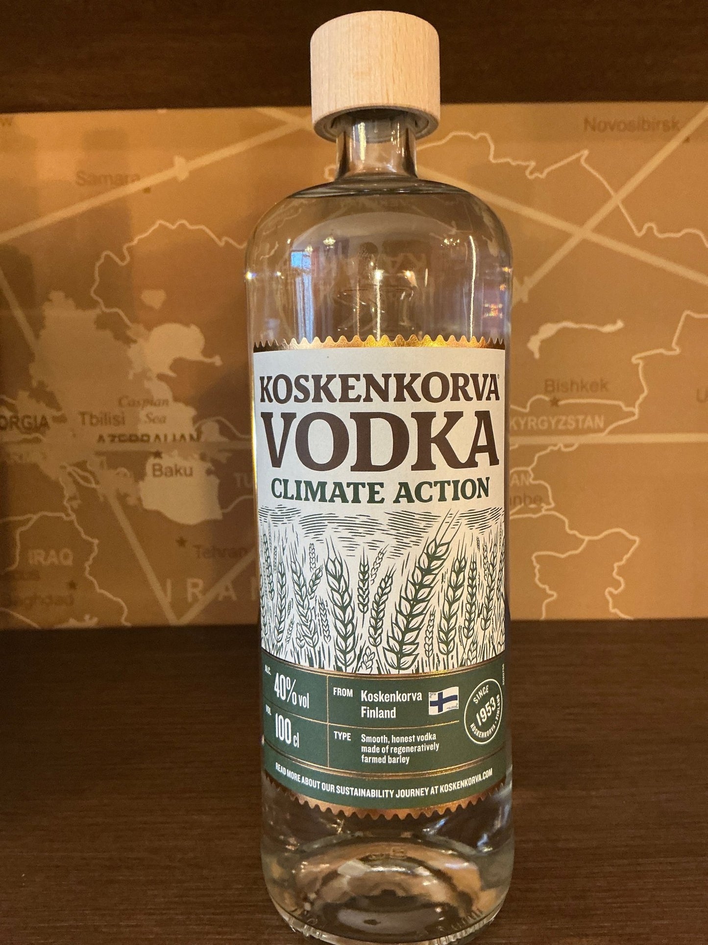 Clear bottle of Koskenkorva Climate Action Vodka with wooden cap, featuring artisanal label highlighting craft, premium.