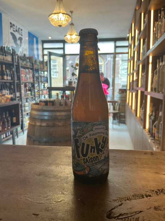 Kromme Haring Funky Saison craft beer bottle with colorful label featuring blue and gold accents on wooden table in artisan.