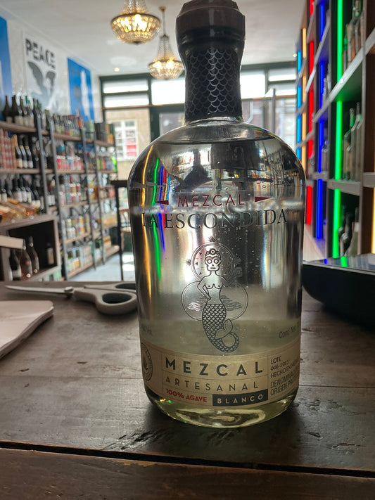 Clear glass bottle of La Escondida Mezcal Reposado with black textured cap and embossed label, highlighting premium.