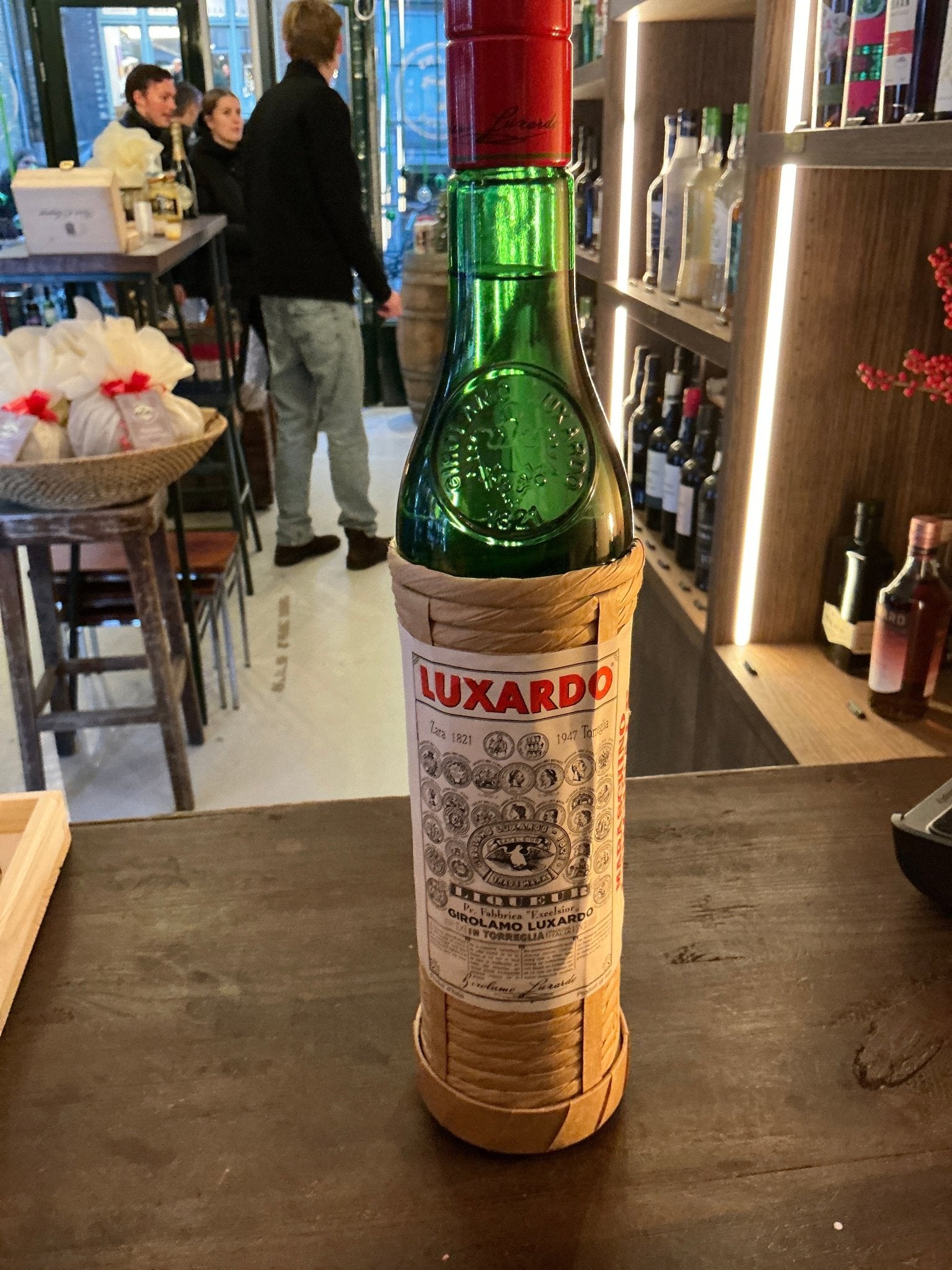 Tall green glass bottle of Luxardo Maraschino Originale cherry liqueur with detailed vintage-style label, red cap, displayed .