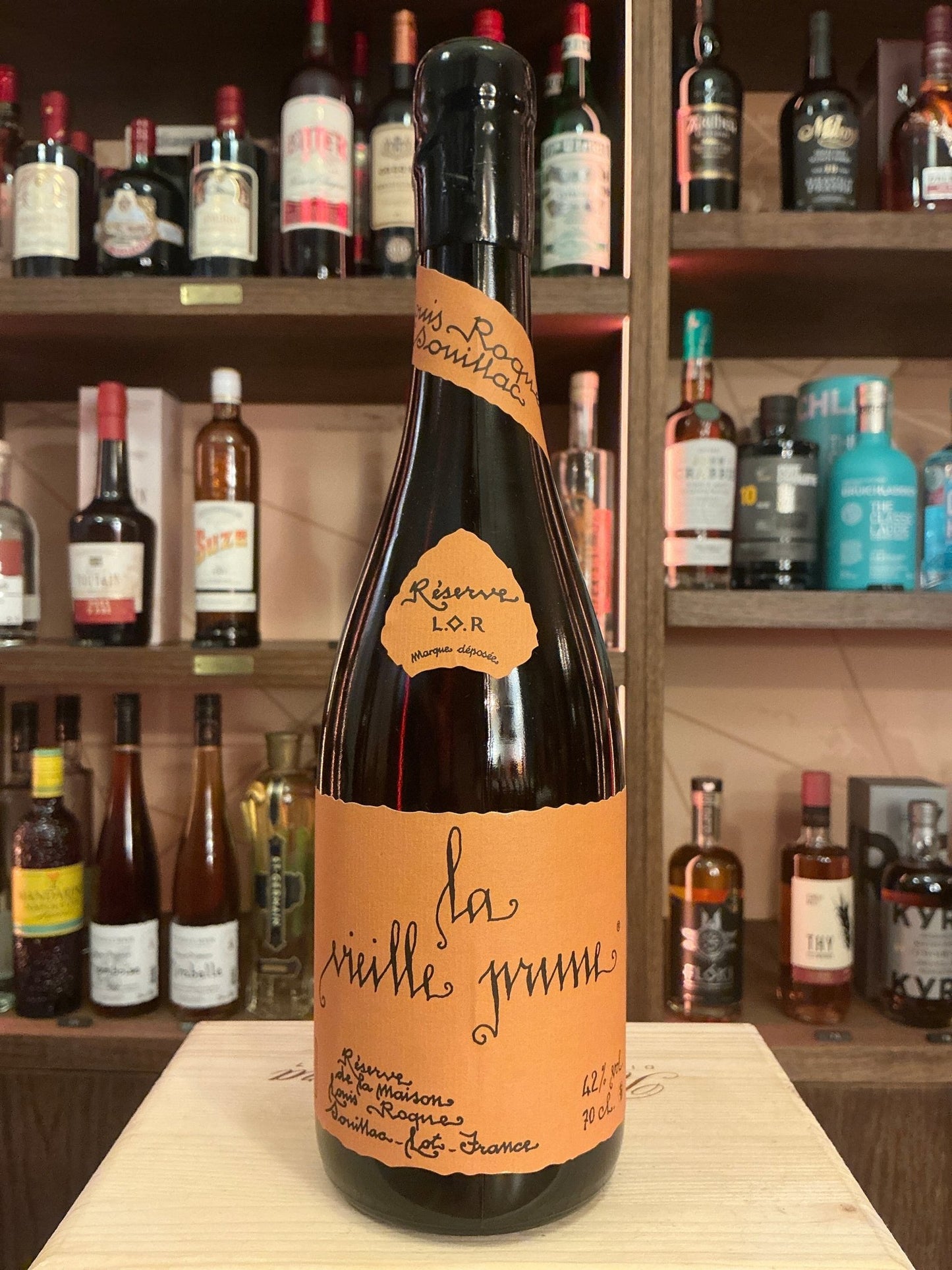 Louis Roque La Vieille Prune plum brandy bottle with orange label, artisanal small batch distilled specialty spirit on.