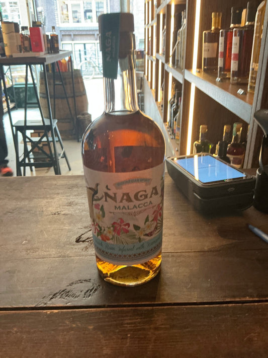 Naga Rum Malacca Indonesian spiced rum bottle with amber liquid, artisan small-batch botanical spirit on wooden table in.