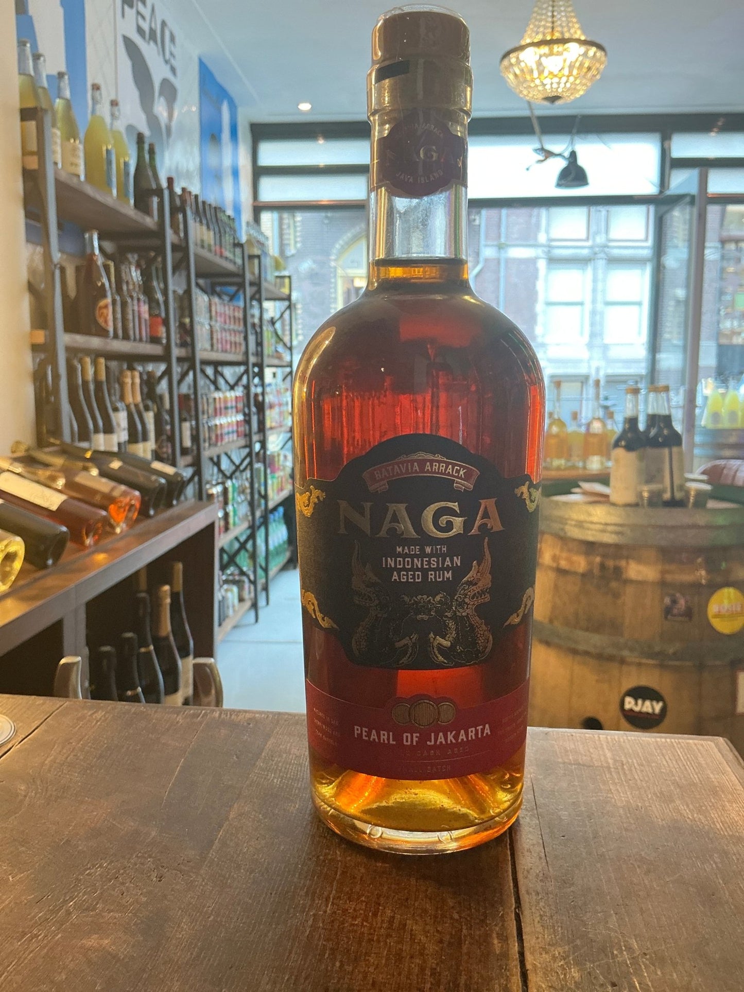 Naga Triple Cask Aged Rum bottle with deep amber liquid, artisan small-batch Indonesian spiced rum, premium specialty.