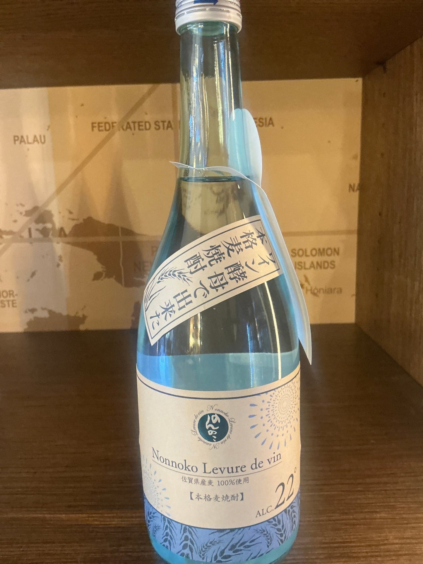 Clear glass bottle of Nonnoko Levure de Vin Honkaku Shochu with artisanal Dutch label showcasing premium barley shochu,.