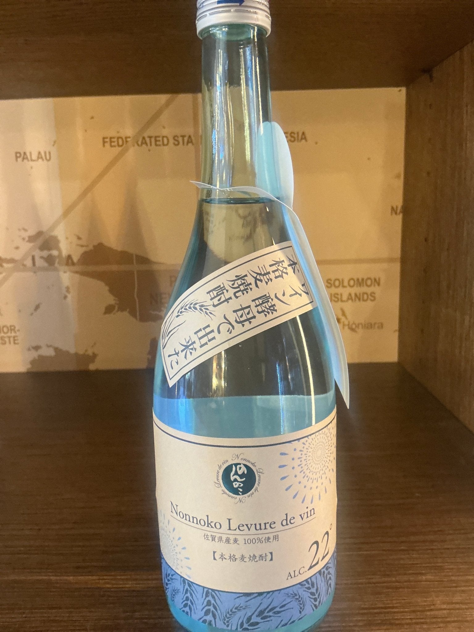 Clear glass bottle of Nonnoko Levure de Vin Honkaku Shochu with artisanal Dutch label showcasing premium barley shochu,.
