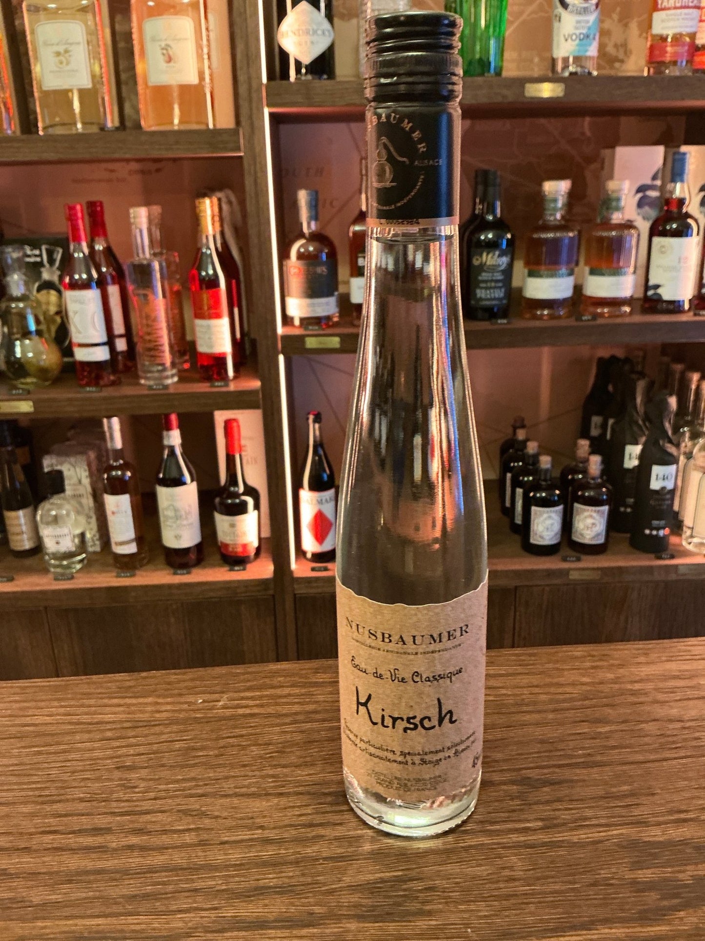 Tall slender clear glass bottle of Nusbaumer Vieux Kirsch Reserve cherry eau-de-vie brandy with aged, distilled artisan.