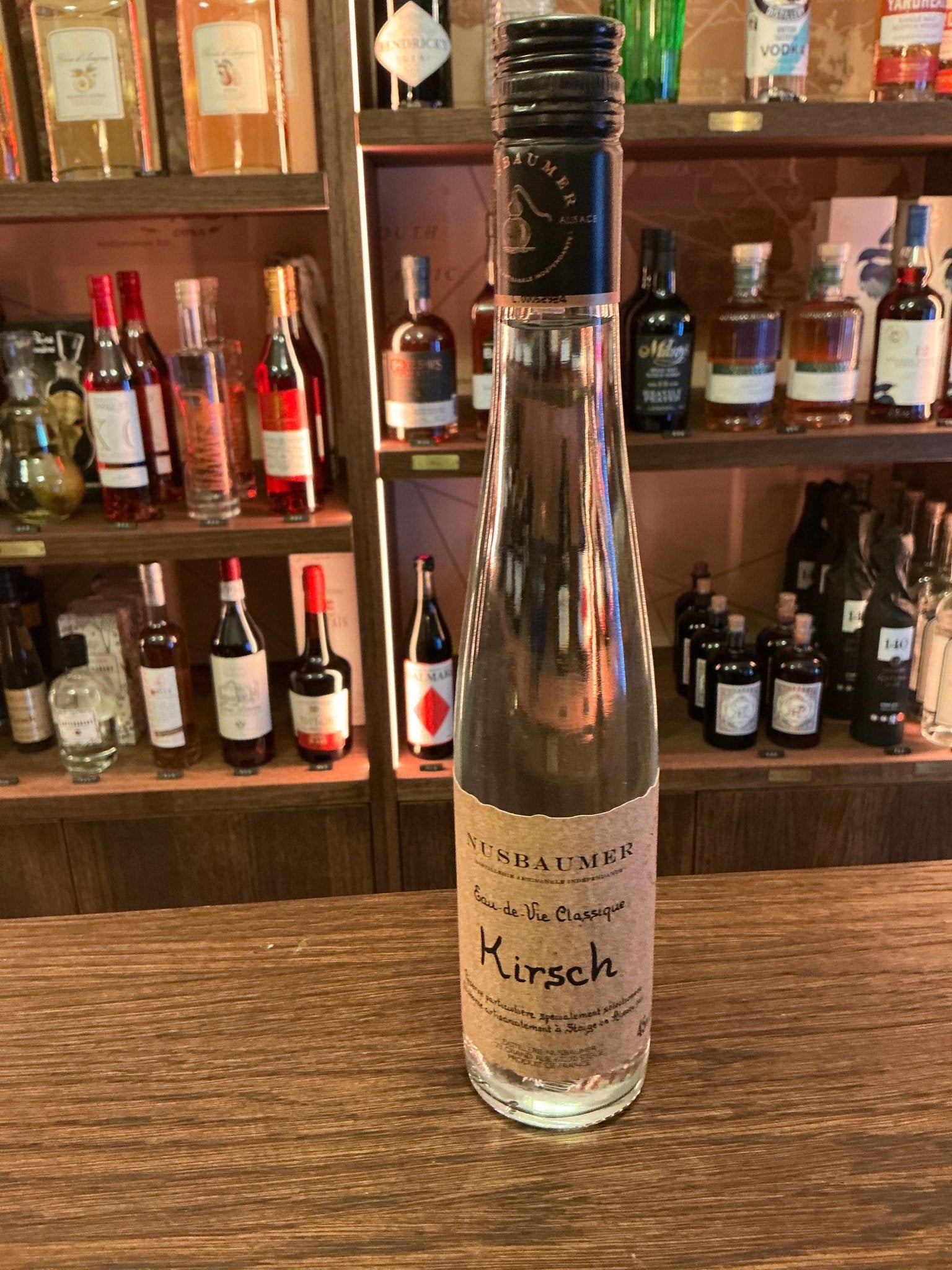 Tall slender clear glass bottle of Nusbaumer Vieux Kirsch Reserve cherry eau-de-vie brandy with aged, distilled artisan.
