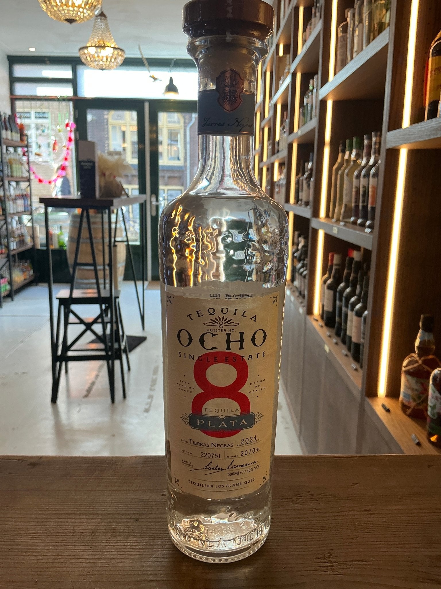 Ocho Blanco Tequila premium clear glass bottle with red number 8 label, small batch artisan distilled spirit.