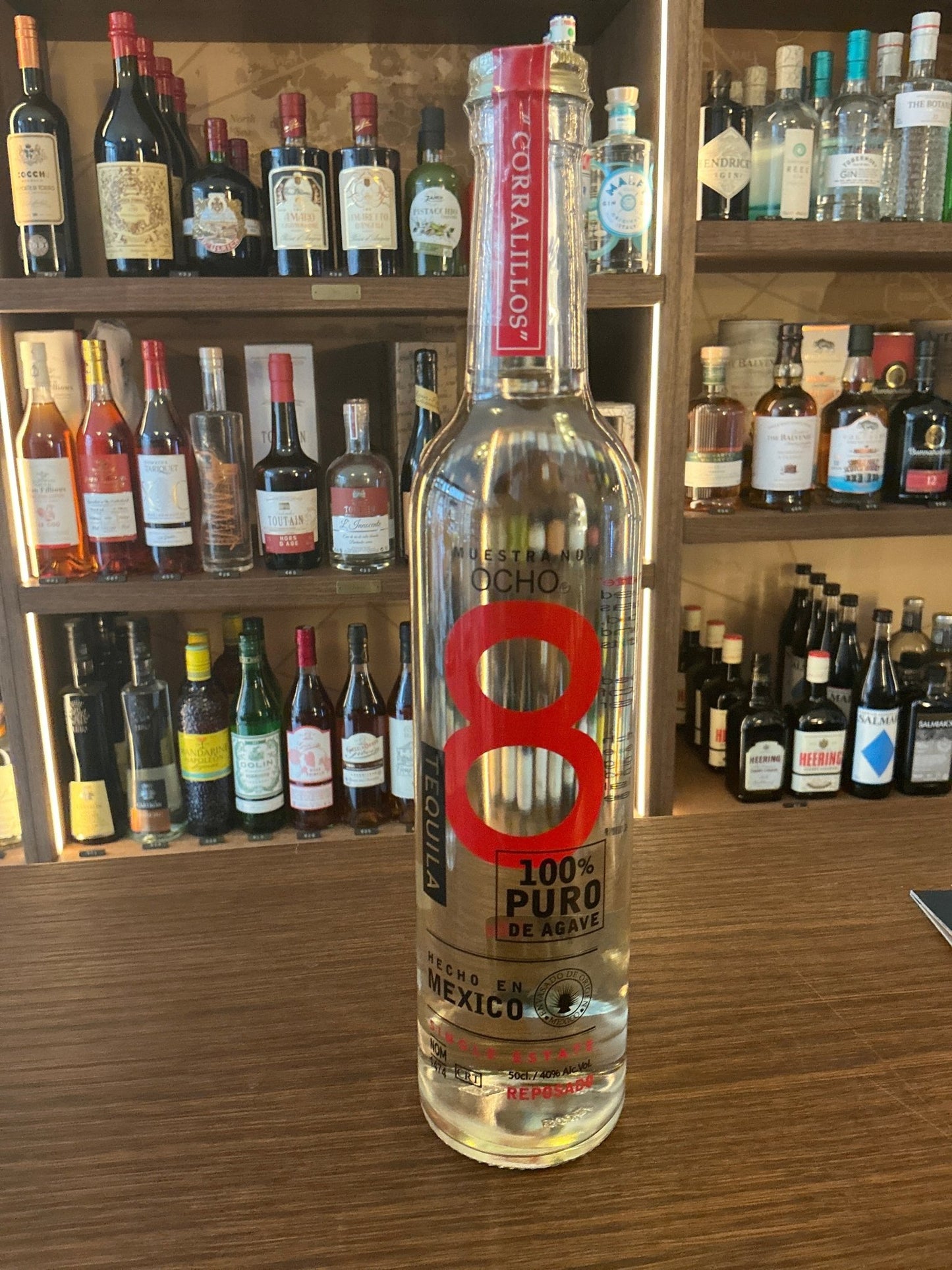 Tall clear bottle of Ocho Reposado Tequila with red and black branding, labeled 100% puro agave and premium distilled.