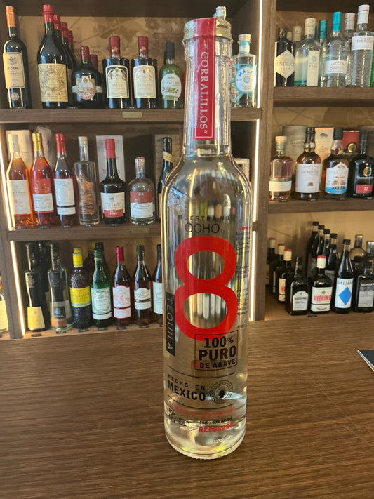 Tall clear bottle of Ocho Reposado Tequila with red and black branding, labeled 100% puro agave and premium distilled.