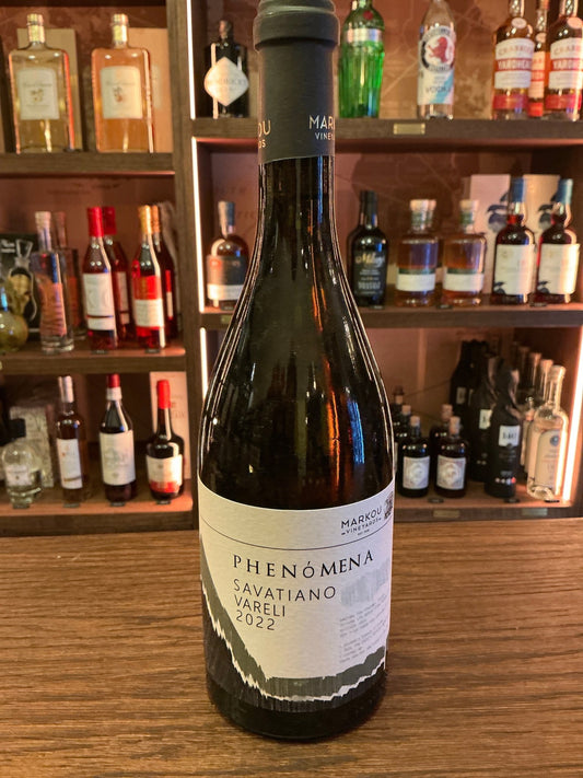 Phenomena Savatiano white wine bottle with minimalist label on wooden bar counter, surrounded by premium artisan spirits.