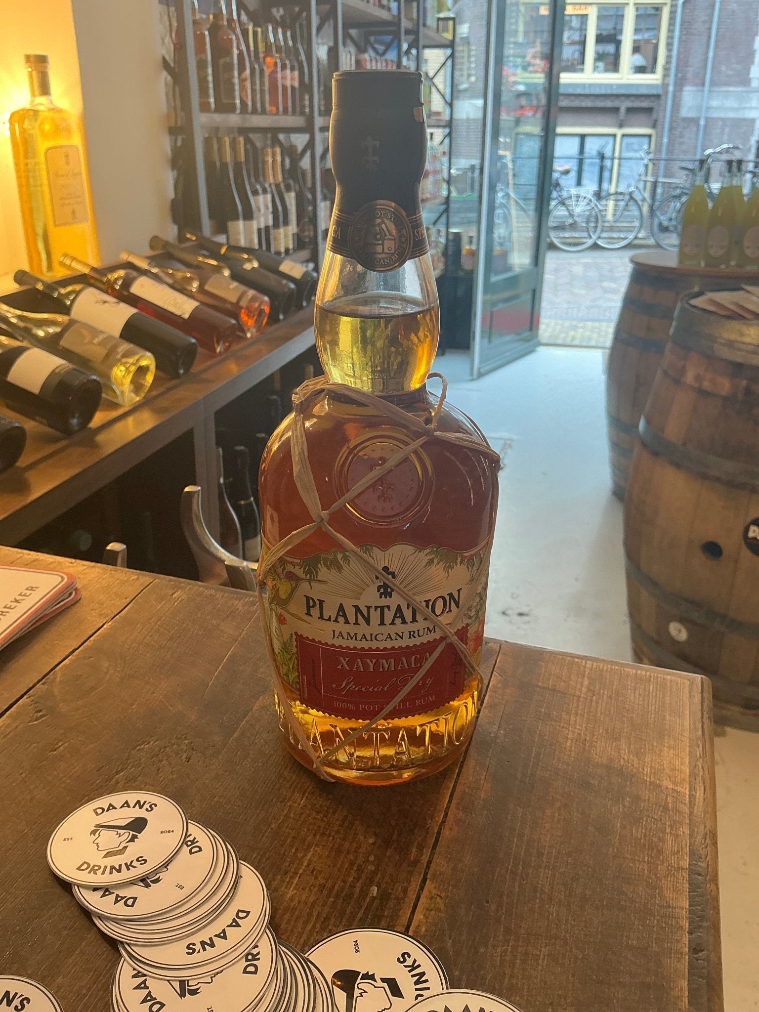 Plantation Xaymaca Special Dry aged rum bottle with amber liquid, premium artisan small-batch Caribbean rum on wooden bar.
