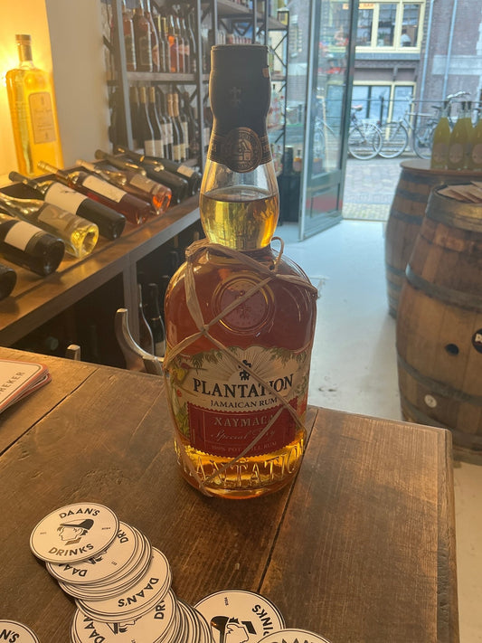 Plantation Xaymaca Special Dry aged rum bottle with amber liquid, premium artisan small-batch Caribbean rum on wooden bar.