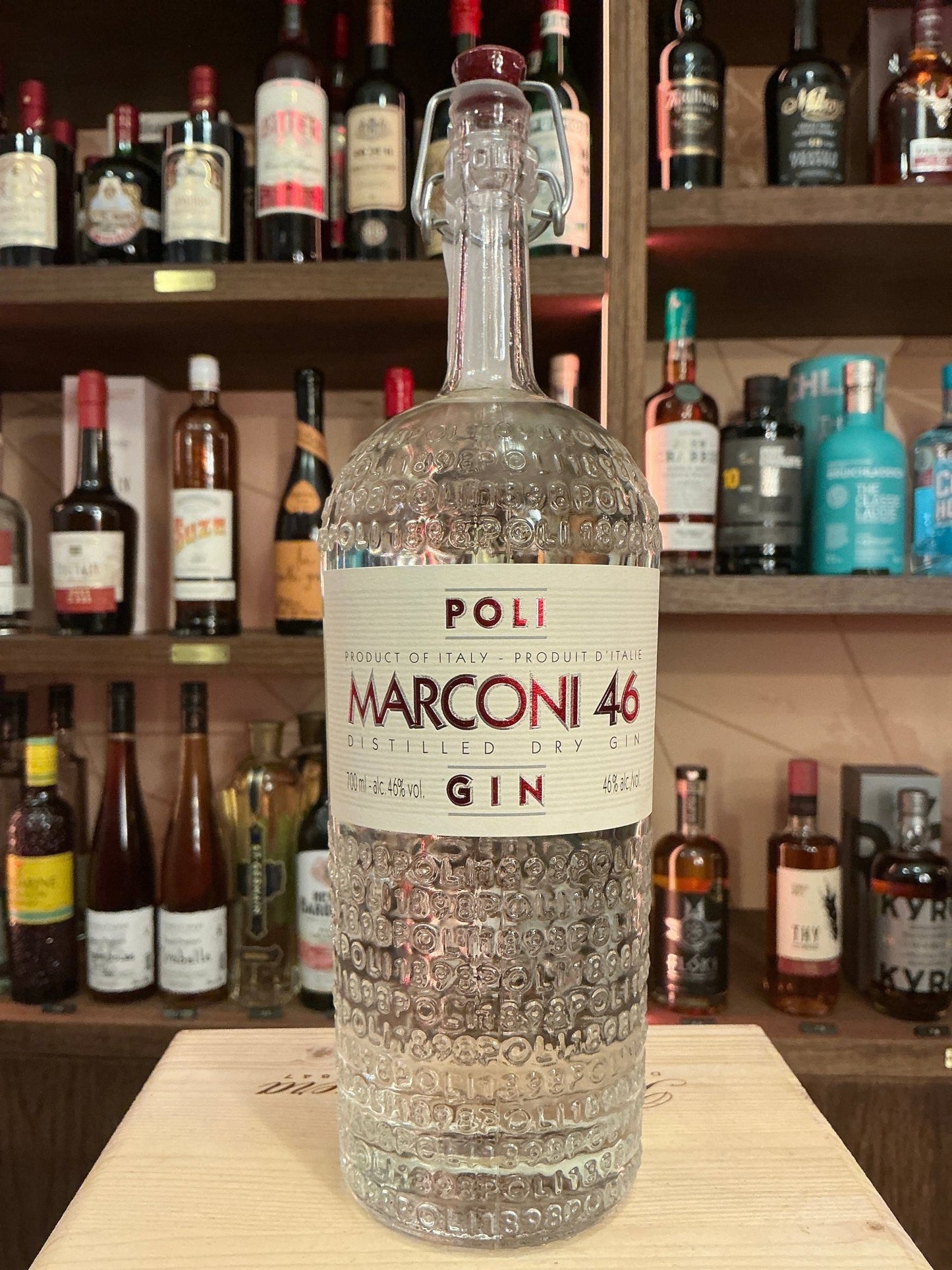 Poli Marconi 46 artisanal distilled gin bottle with textured glass, premium botanical spirit on wooden counter, specialty.