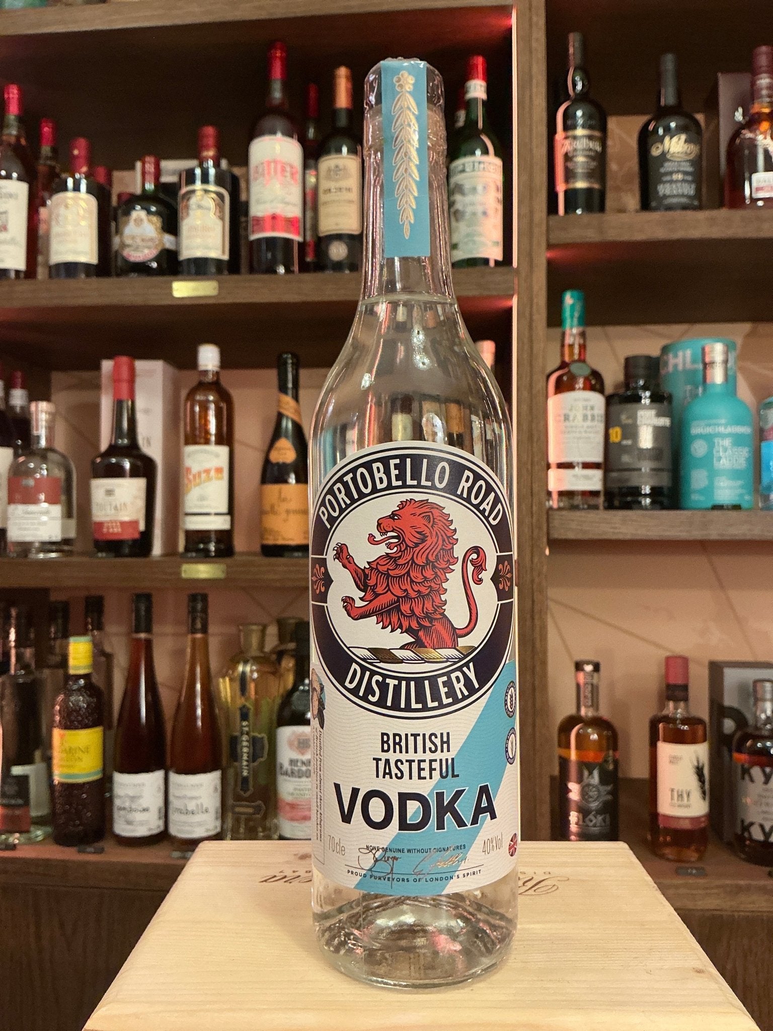 Clear glass bottle of Portobello Road Distillery British Tasted Vodka with a red lion logo, blue cap, and premium artisan.