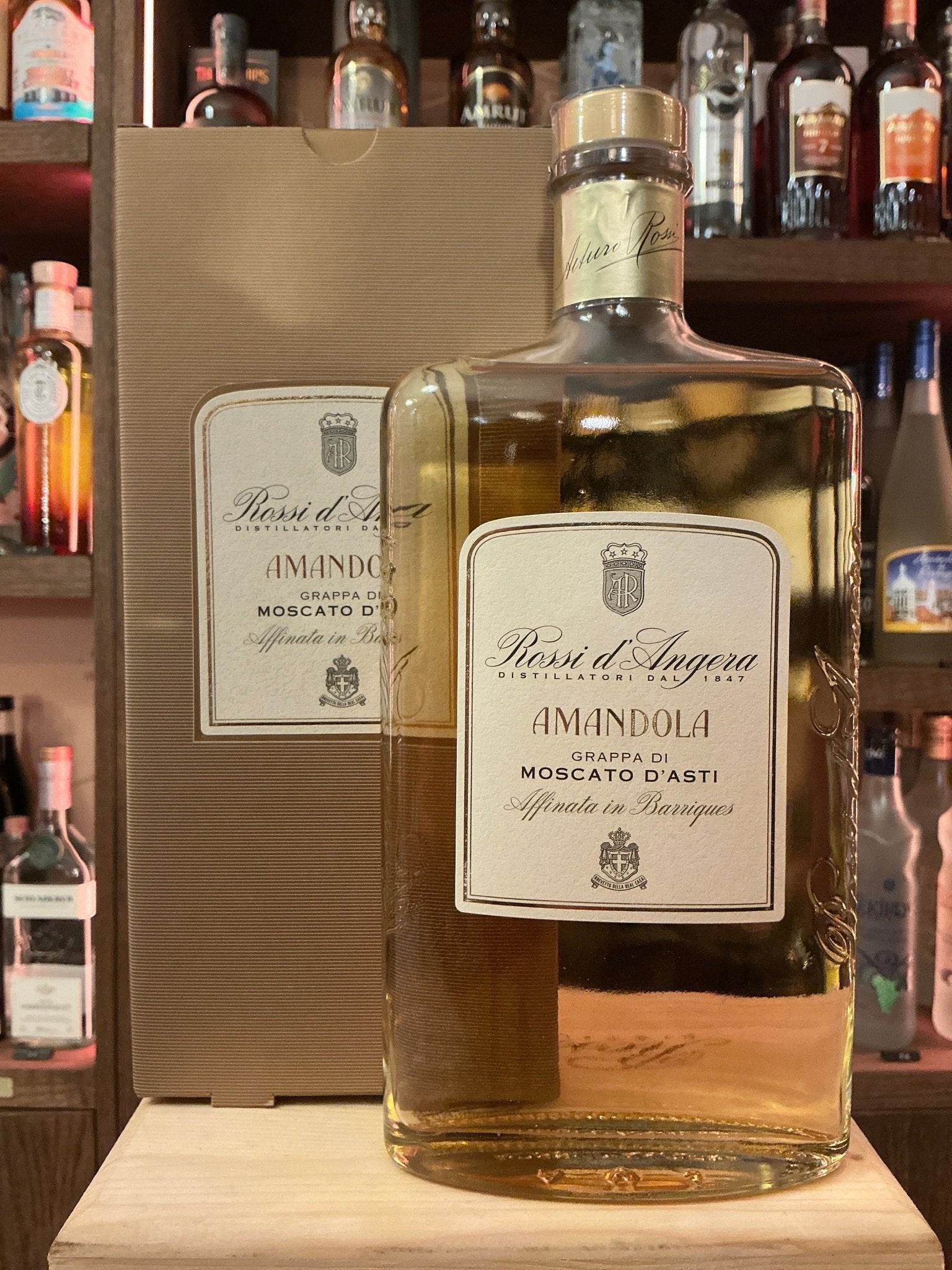 Rossi D’Angera Amandola Moscati D’Asti premium artisan brandy bottle with golden amber liquid and cream label, displayed.