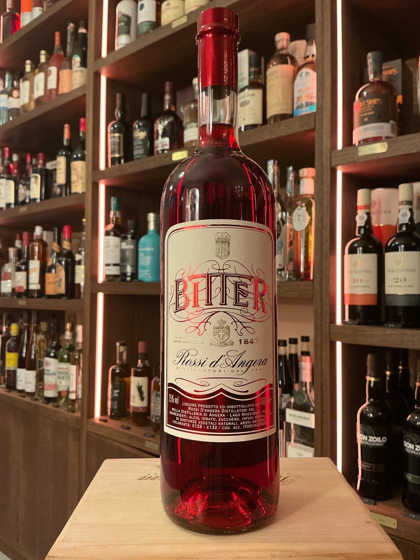 Rossi D’Angera Bitter red botanical liqueur bottle with vintage-style label on wooden table, artisan specialty spirits.