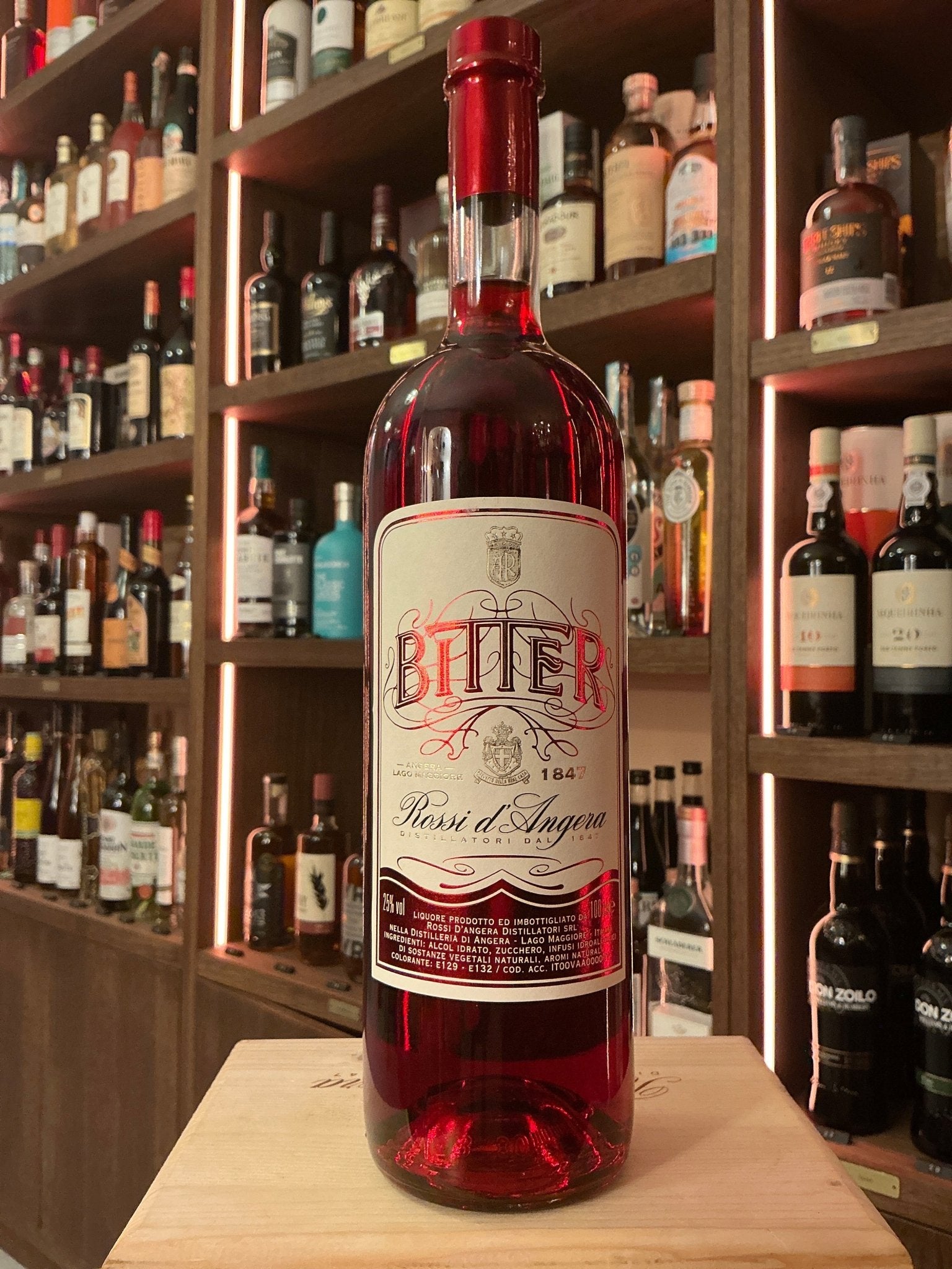 Rossi D’Angera Bitter red botanical liqueur bottle with vintage-style label on wooden table, artisan specialty spirits.