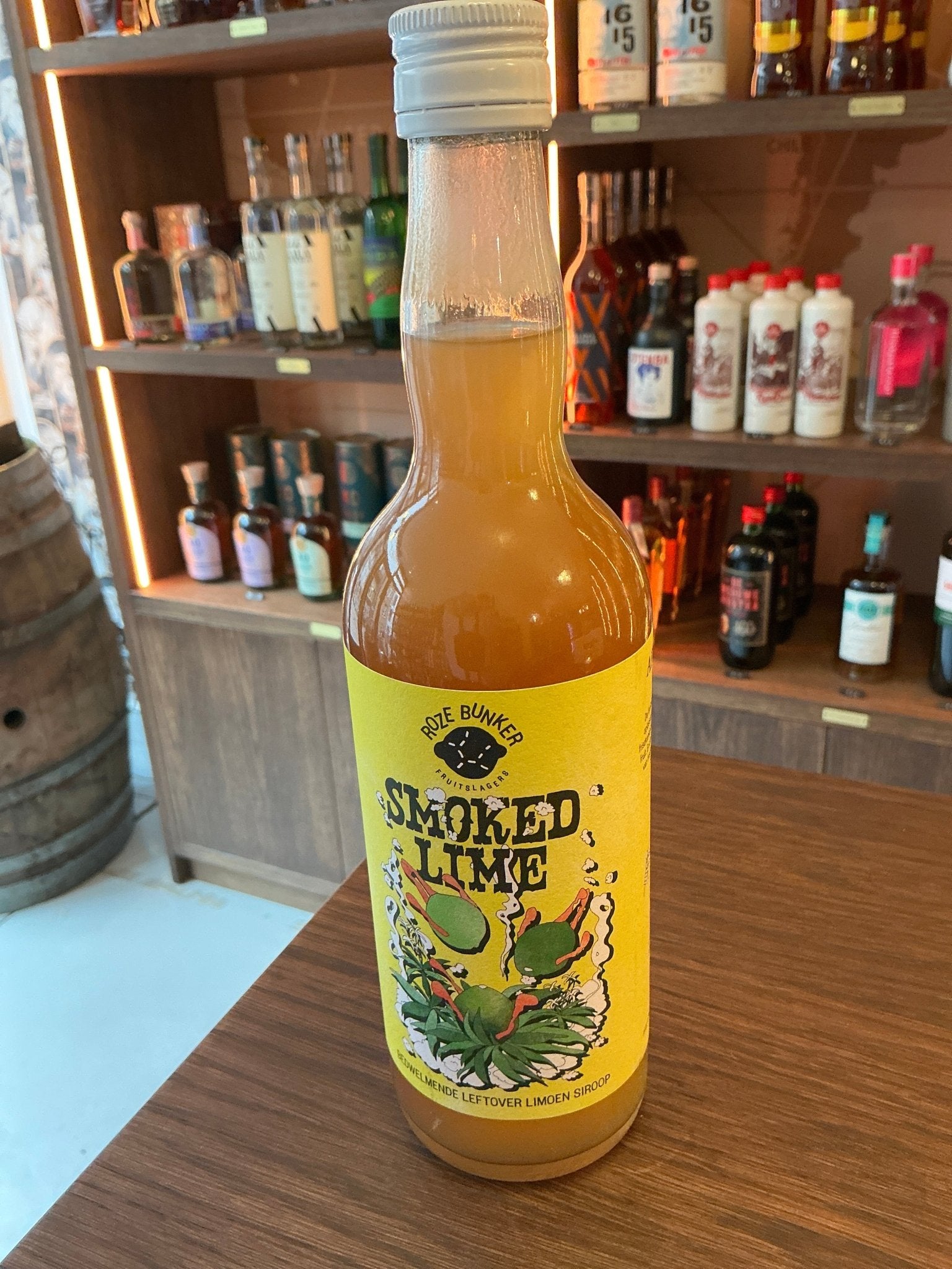 Roze Bunker Smoked Lime cordial bottle with vibrant yellow label featuring botanical and spiced lime illustration on wooden.