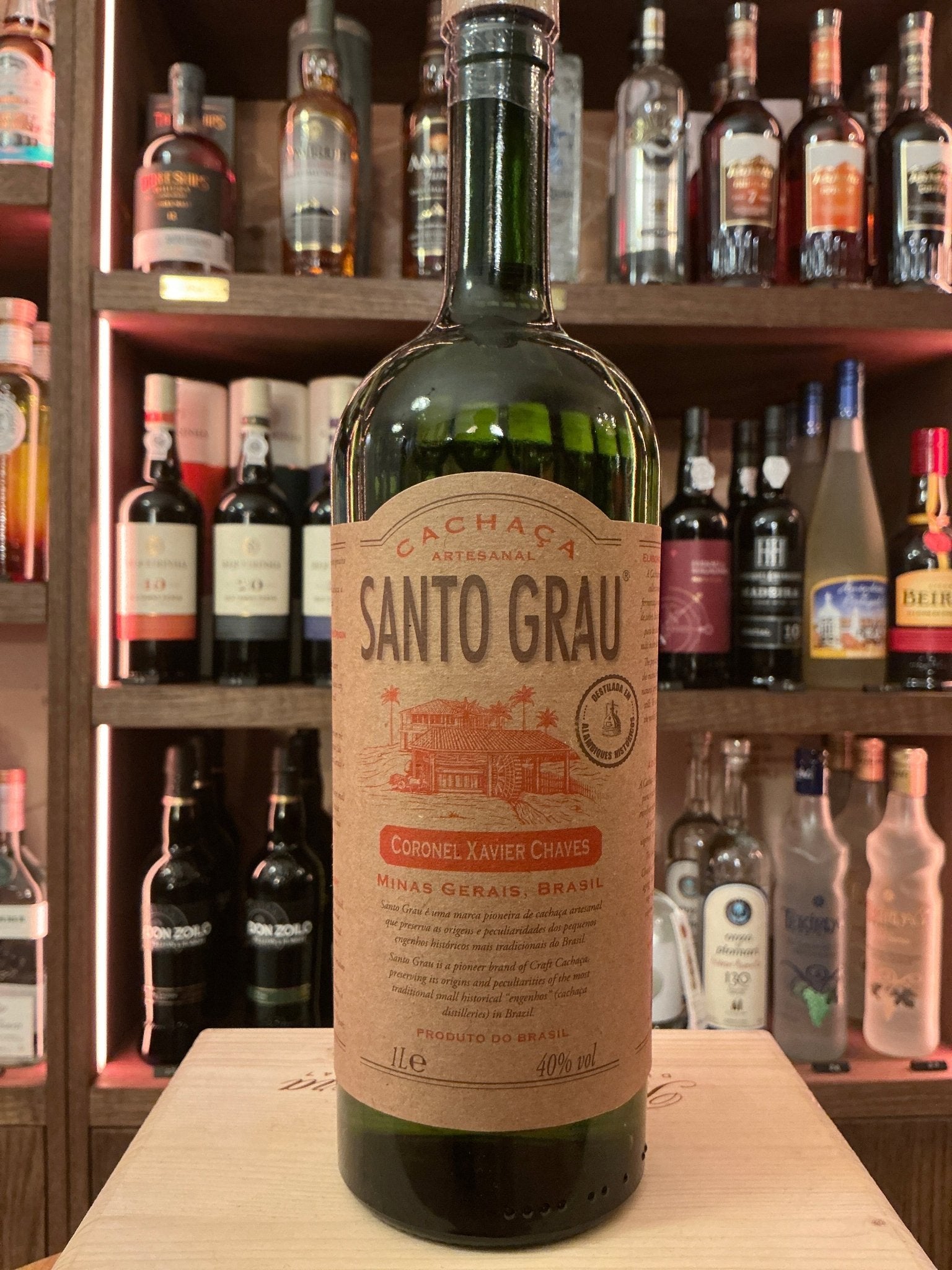 Green glass bottle of Santa Grau Cachaça with beige label featuring botanical and spiced design, artisan small batch.