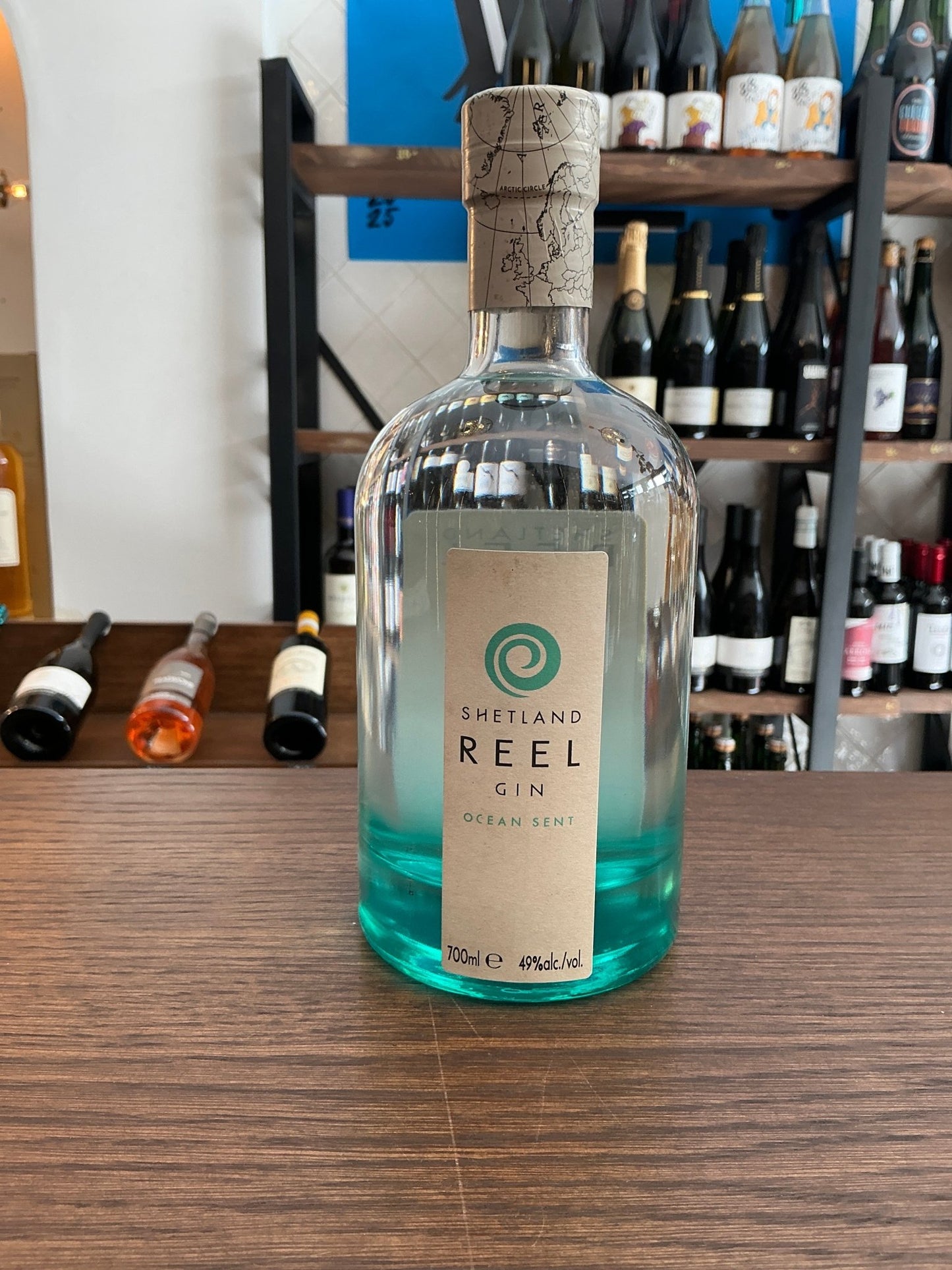 Shetland Reel Ocean Sent Gin bottle with clear glass, turquoise liquid base, natural cork stopper, premium small batch.