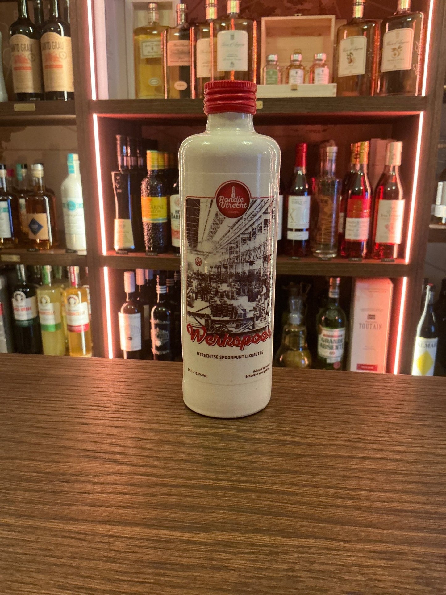 White ceramic bottle of Spoorpunt Likorette artisan Dutch liqueur with red cap and detailed black and red vintage train.