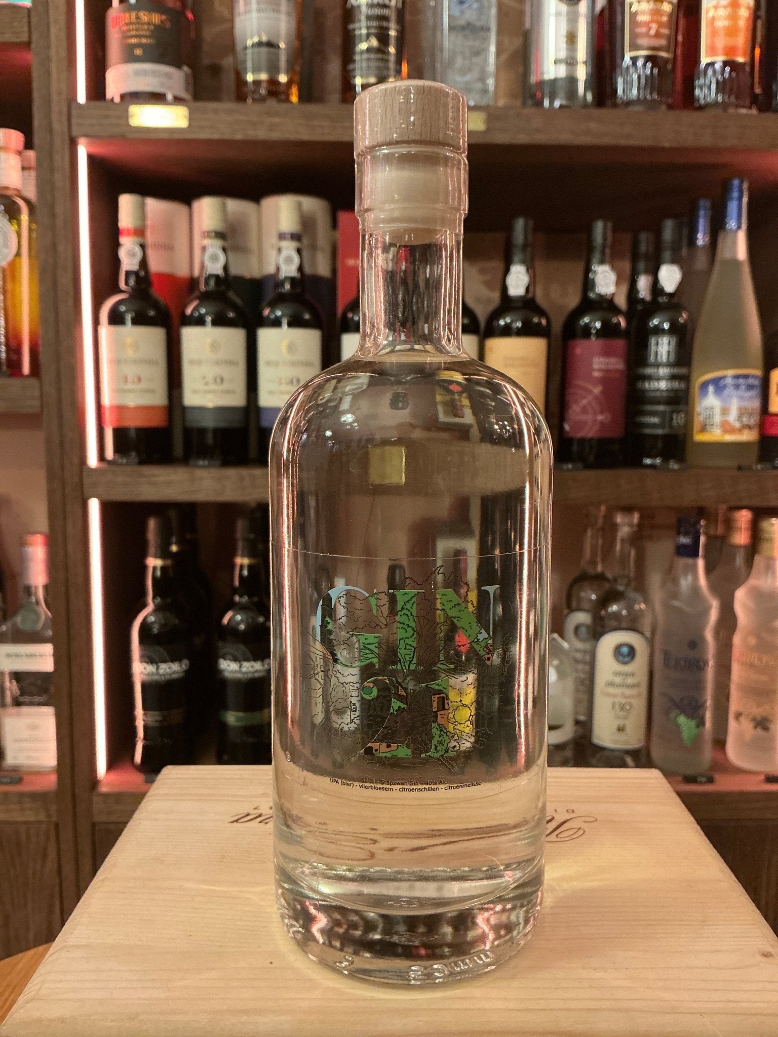 Clear glass bottle of Stapzwan Gin 21 with rustic cork stopper on wooden surface, showcasing premium artisan Dutch small.