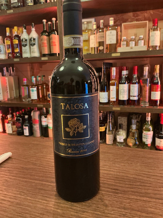 Talosa Vino Nobile di Montepulciano Riserva Italian red wine bottle with dark blue and gold label on wooden bar counter.