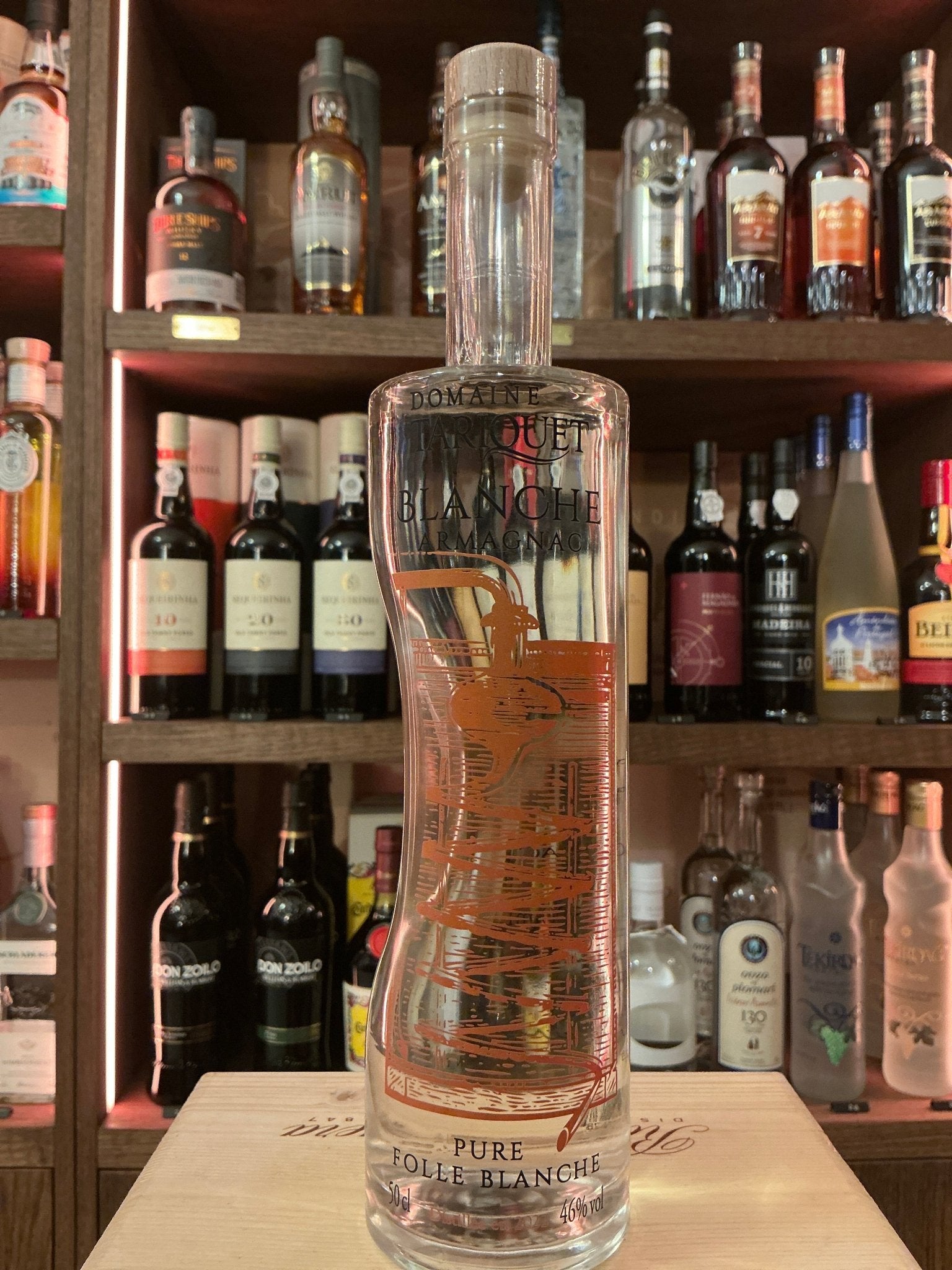Tall clear glass bottle of Tariquet Armagnac Blanche 2022 with refined embossed design, premium small batch brandy,.