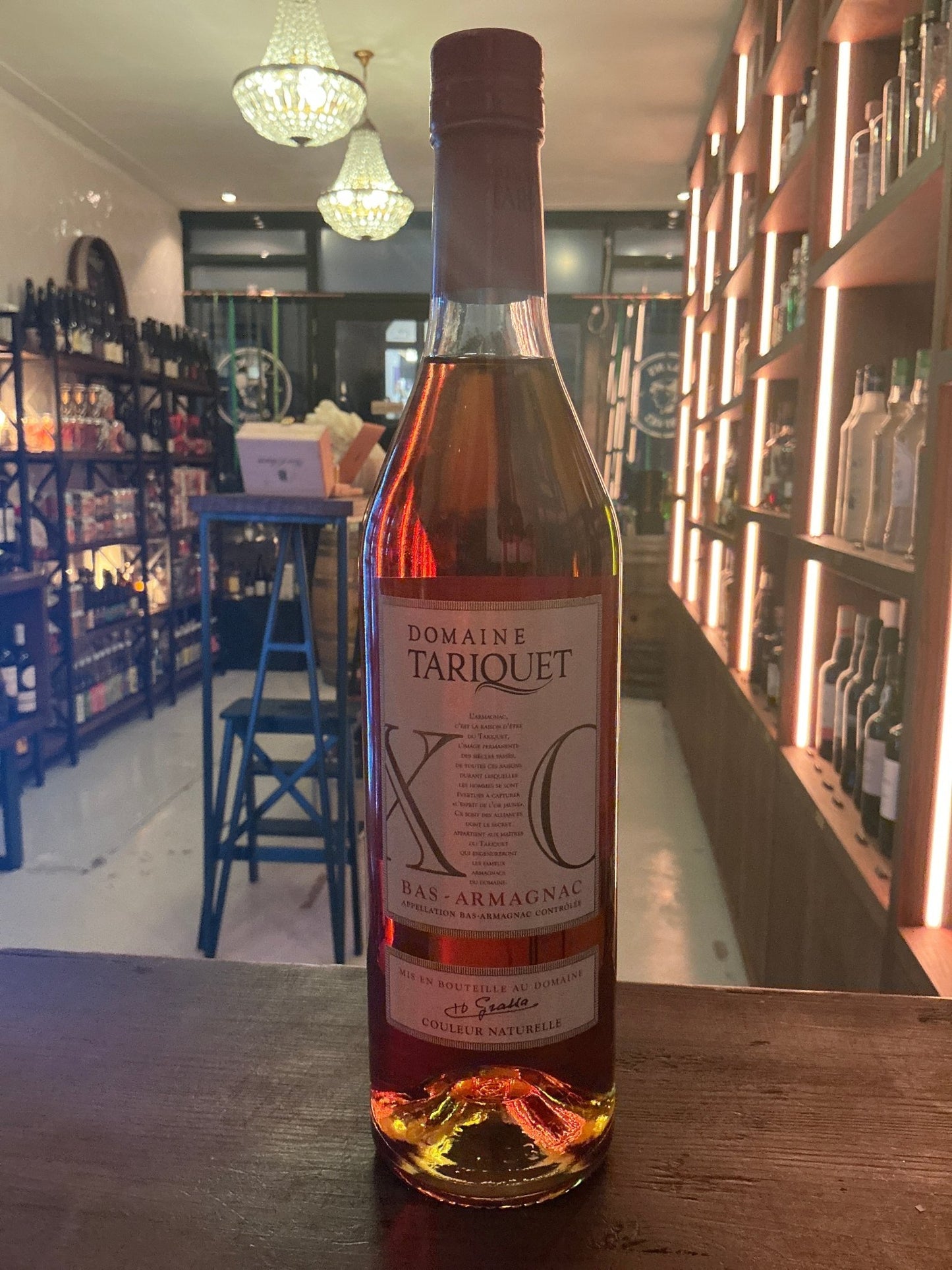 Tall amber glass bottle of Tariquet Bas-Armagnac XO brandy, premium aged and distilled, with a simple cream label and rustic .