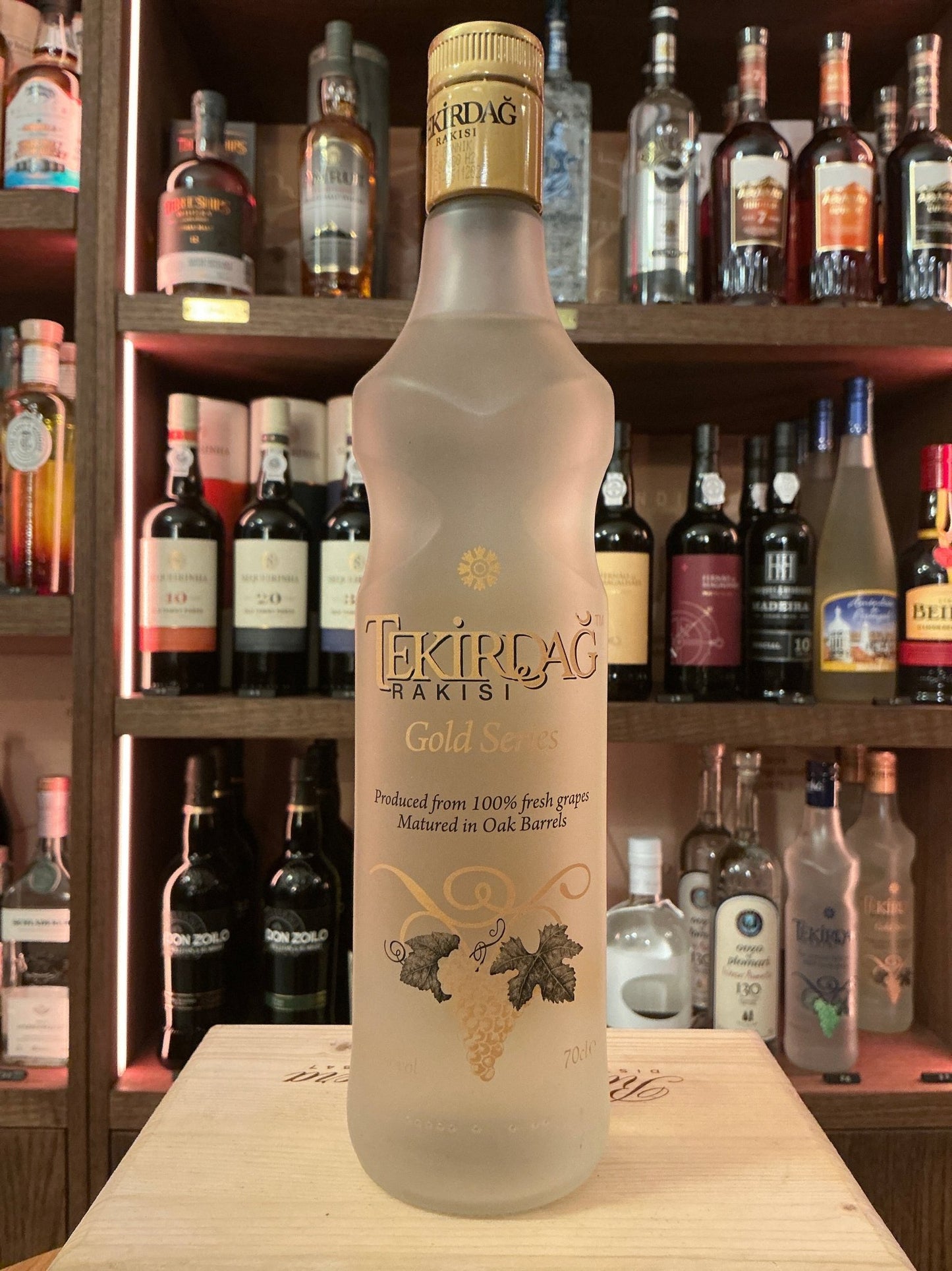 Tekirdağ Gold Raki frosted glass bottle with gold cap, premium Turkish distilled botanical spirit on wooden surface.