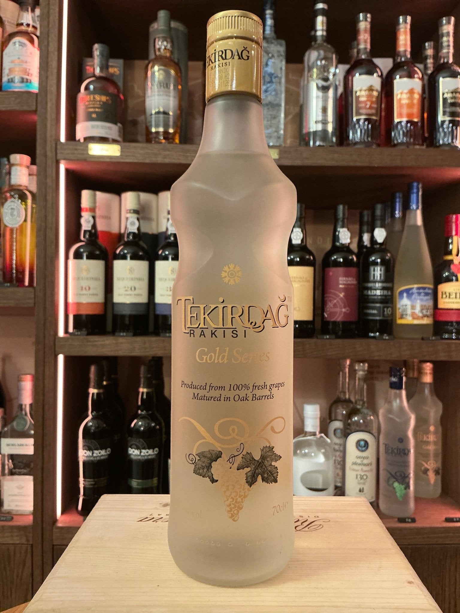 Tekirdağ Gold Raki frosted glass bottle with gold cap, premium Turkish distilled botanical spirit on wooden surface.